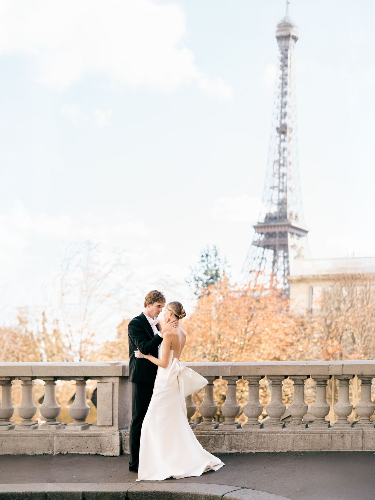 A romantic couple shares an elegant dance pose on a stone balcony with city towers visible in the background.