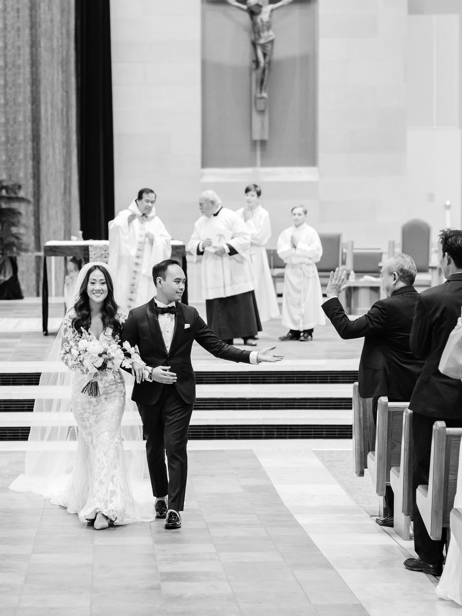 Black and white photo of a newlywed couple walking down the church aisle after their wedding ceremony.