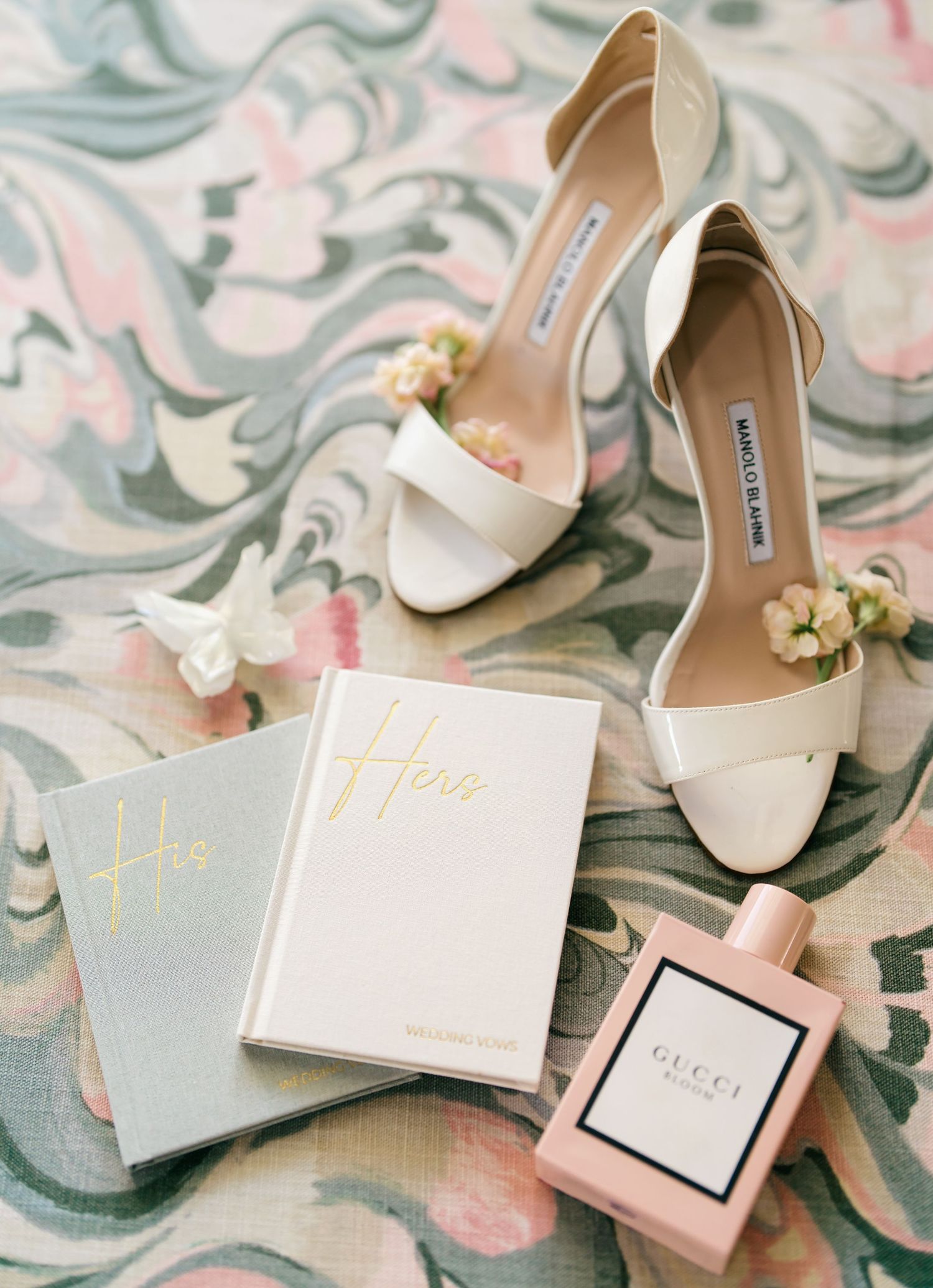 Wedding accessories including cream-colored heels and gray invitation suites on a patterned surface.