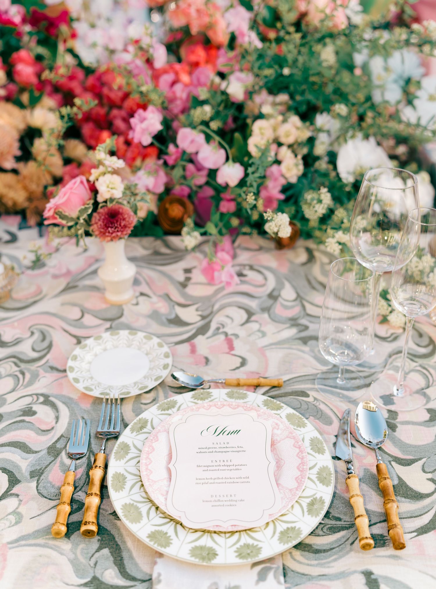 Luxurious table settings with pink and coral floral centerpieces and ornate patterned tablecloths.