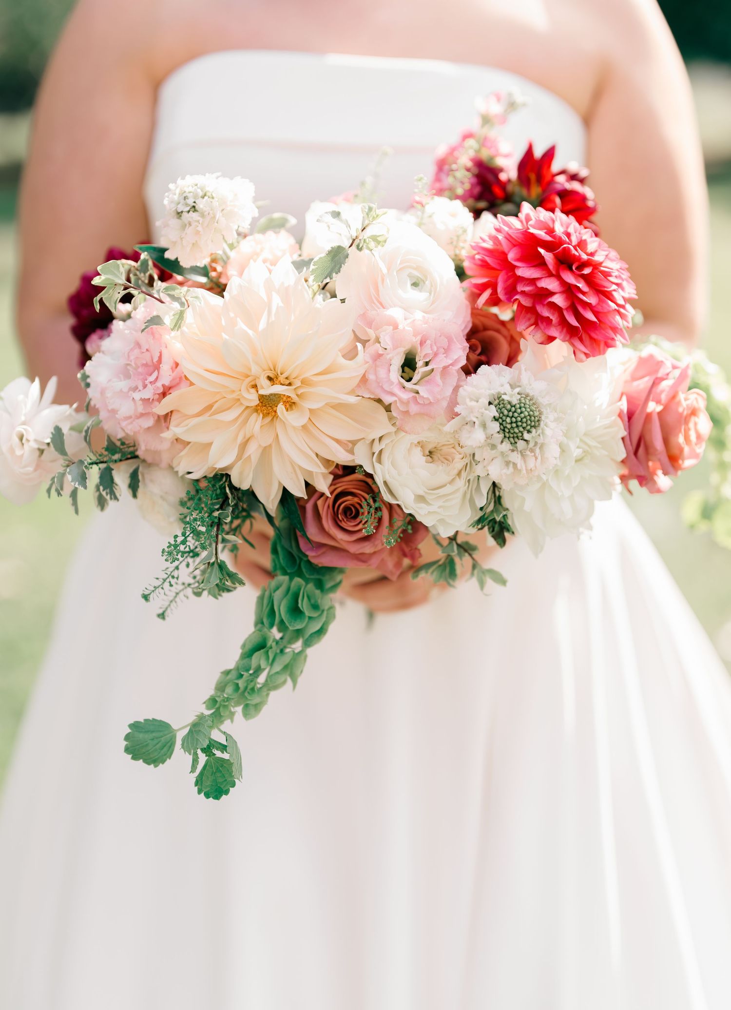 A row of wedding bouquets featuring blush pink dahlias, white roses, and greenery arranged in a soft romantic style.