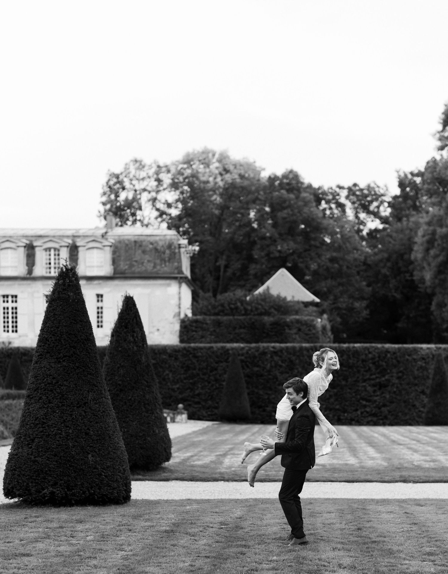 A series of black and white photographs showing people walking through a formal garden with manicured hedges and topiaries.