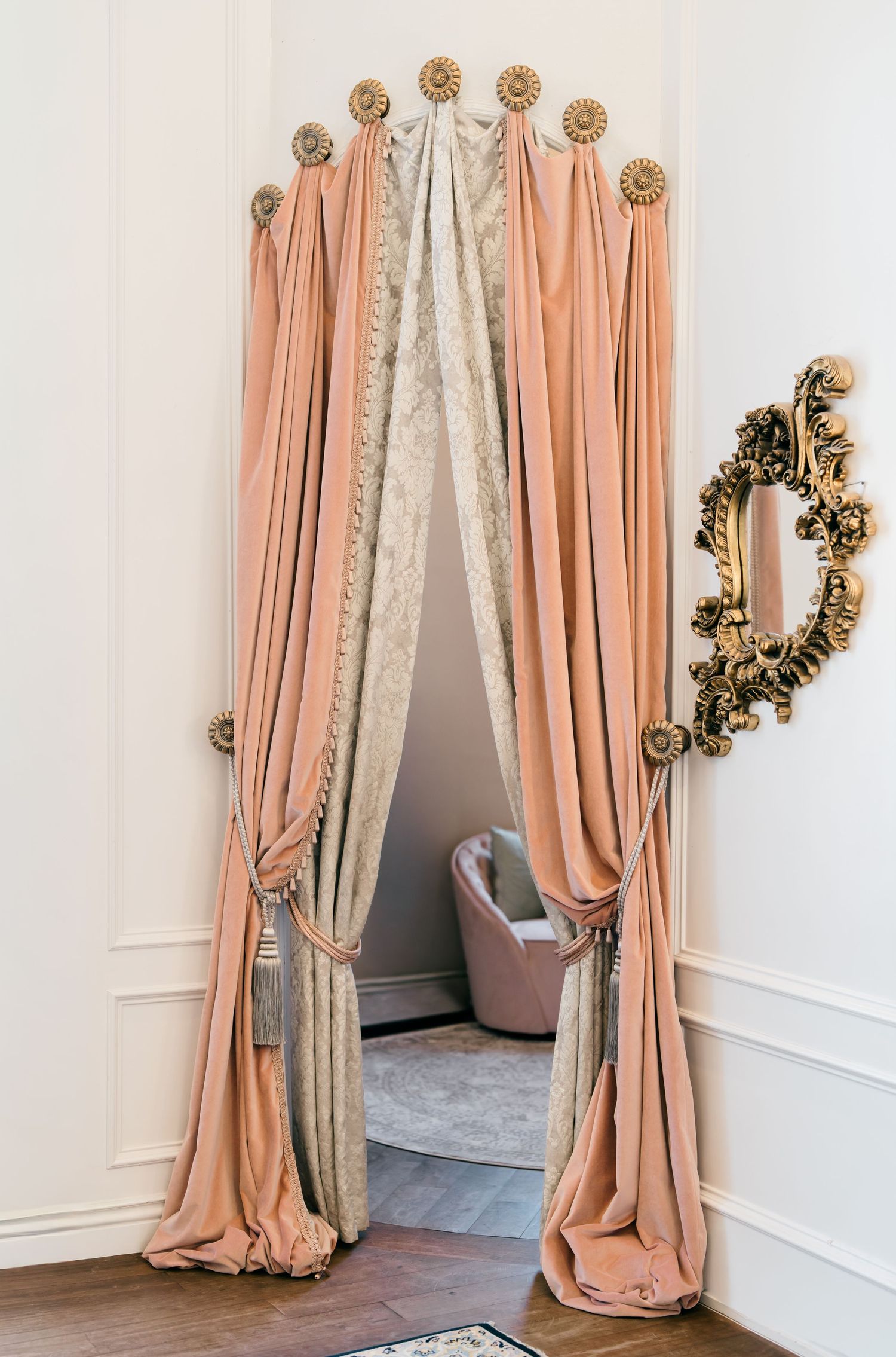 Elegant peach and silver curtain panels with decorative gold accents create a luxurious backdrop in a formal room setting.
