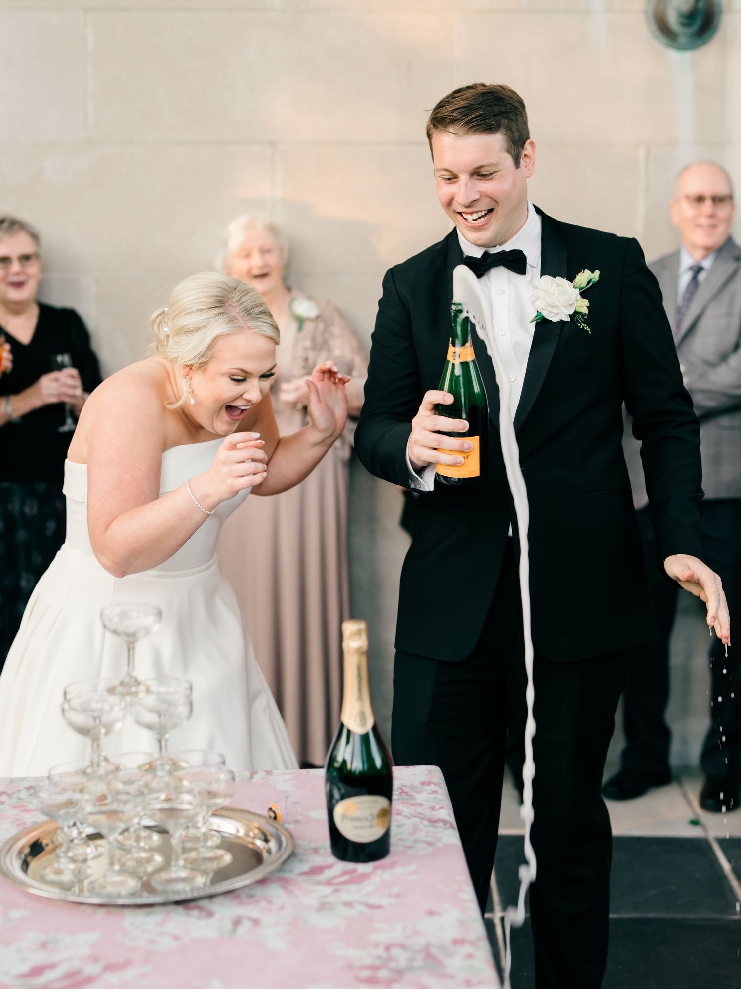 Wedding party members toast with champagne glasses during an elegant celebration at an indoor venue.