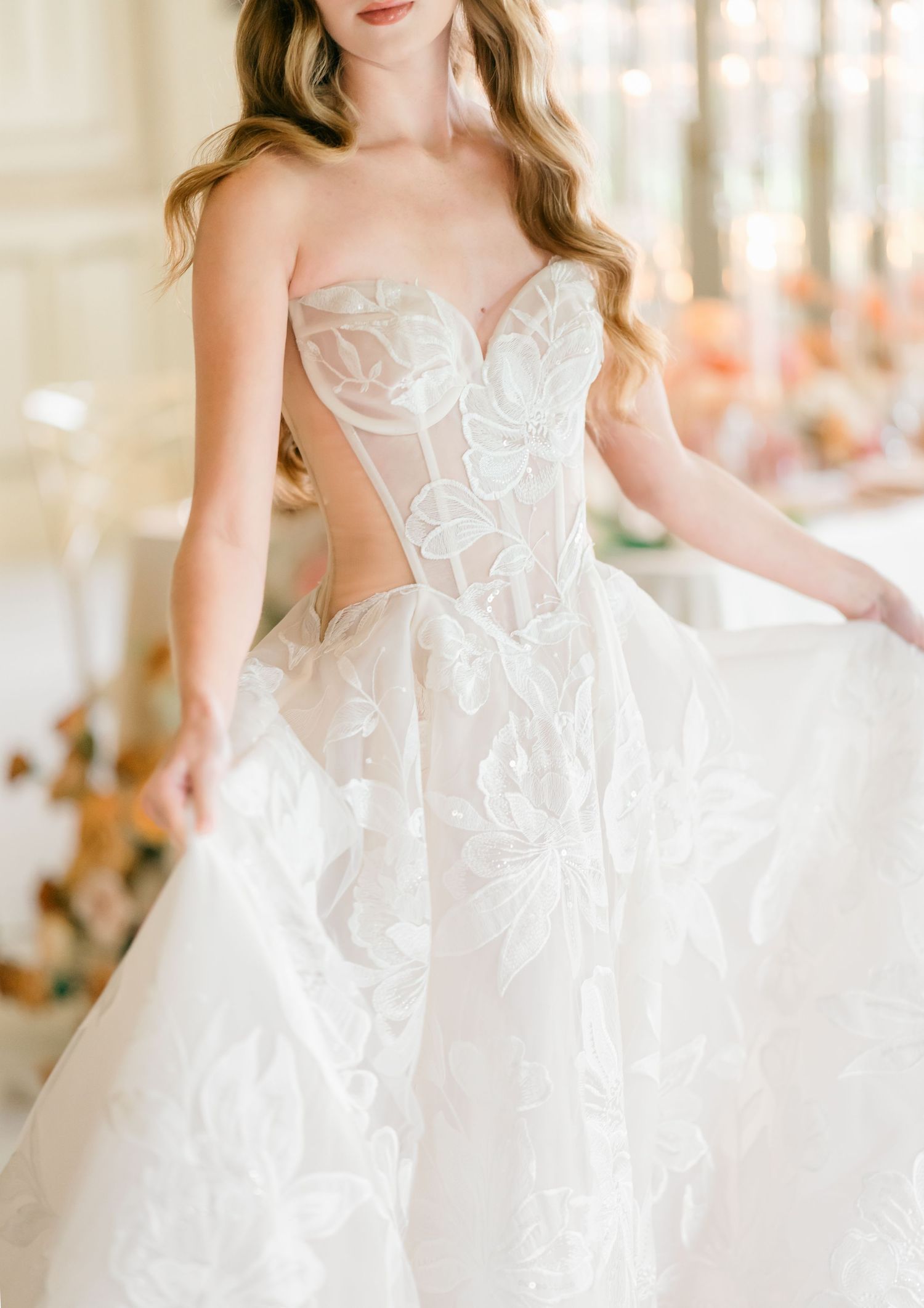 A bride in an elegant white lace wedding gown with floral appliques twirls to show the flowing skirt and train.