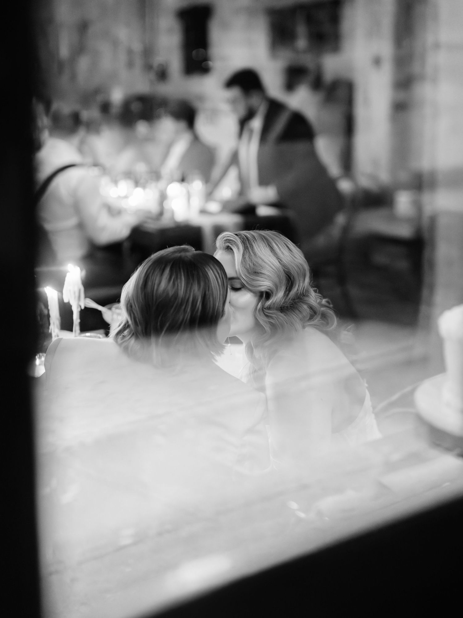 Black and white photo series showing blurred silhouettes of people seated at a long table with candles.