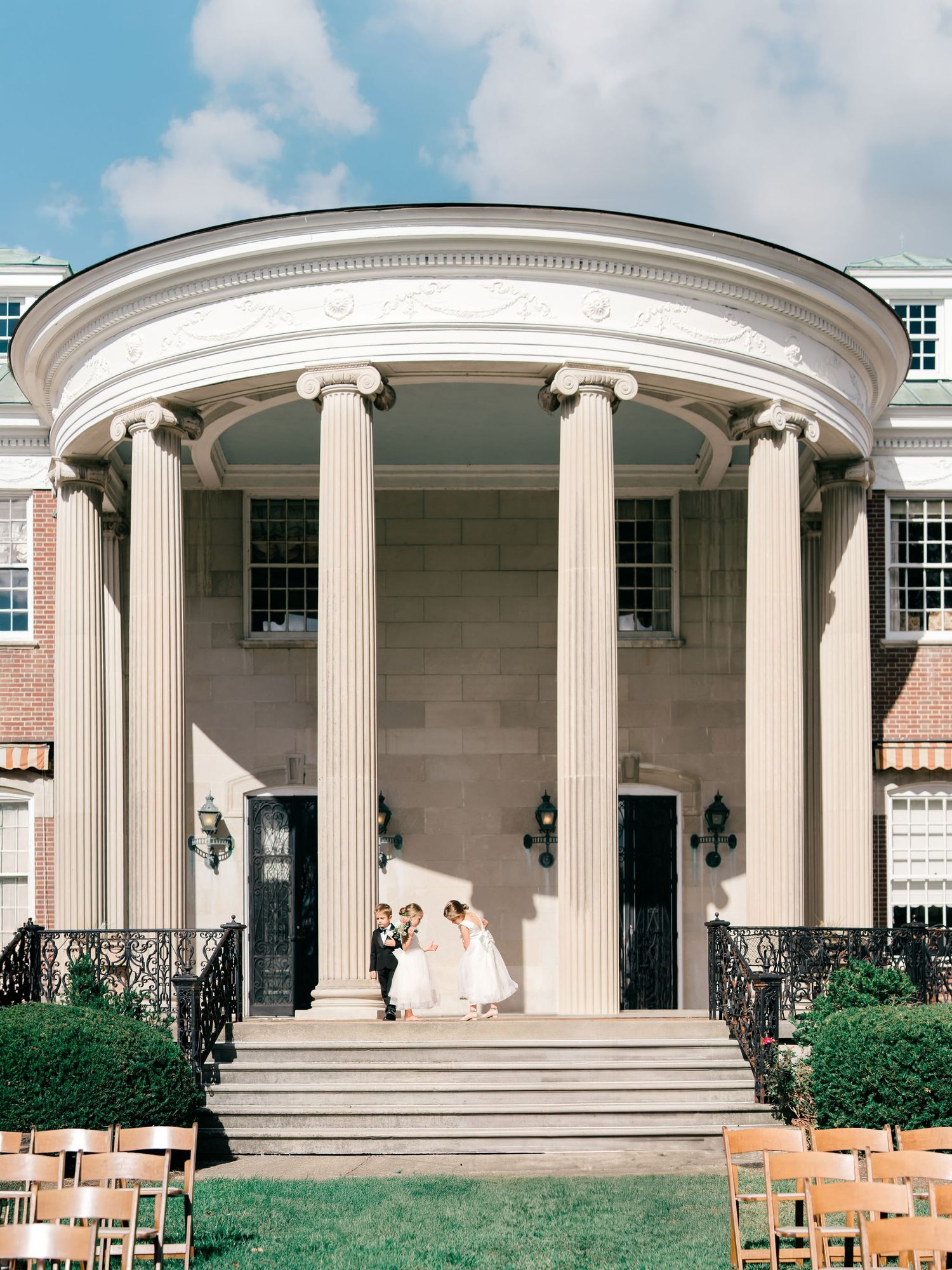 Elegant white columned portico with classical architecture features set against a bright blue sky at an outdoor venue.