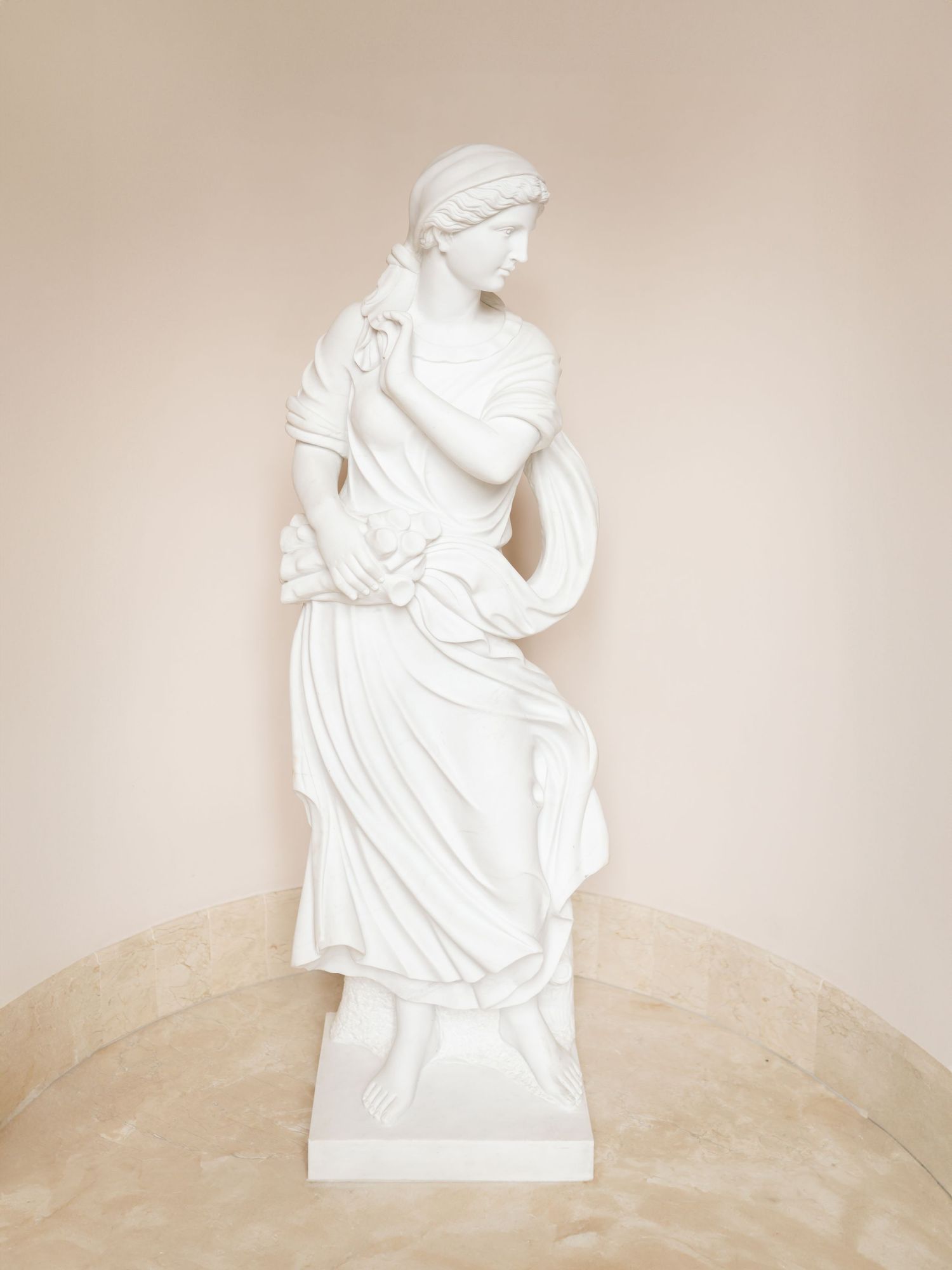 White classical sculptures displayed in a row against a beige wall in an elegant gallery setting.