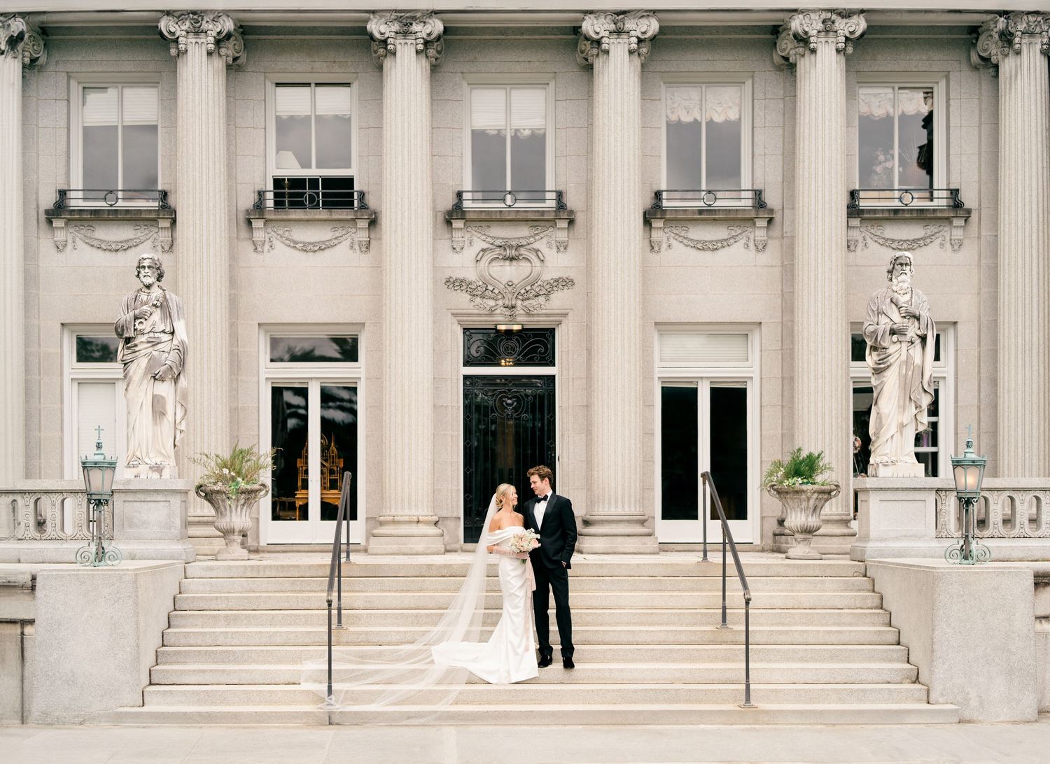 A panoramic view of an elegant wedding ceremony at a grand historic building with white columns and ornate architecture.