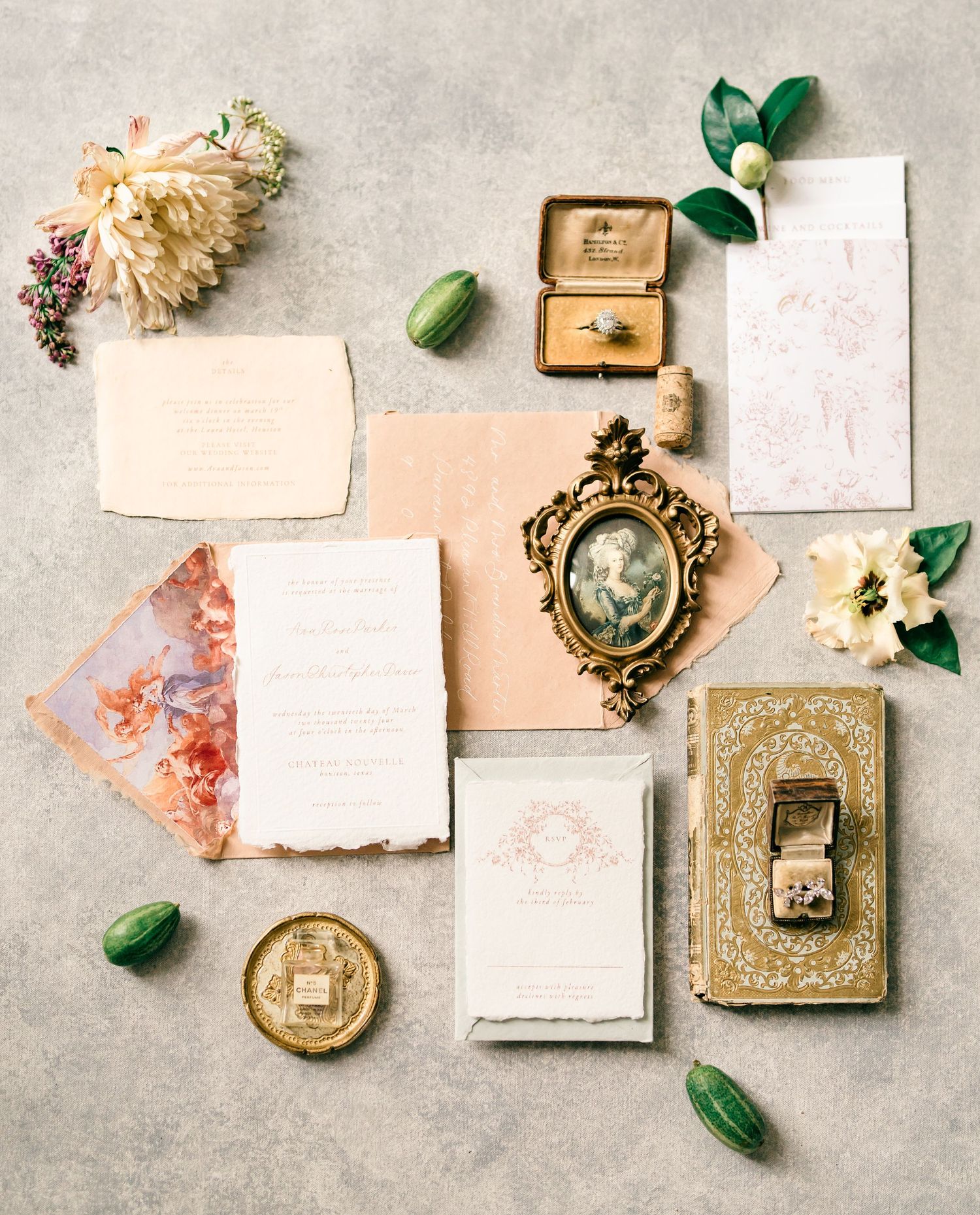 Vintage-inspired wedding styling flatlay with ornate gold frames, dried flowers, and delicate paper pieces on concrete background.
