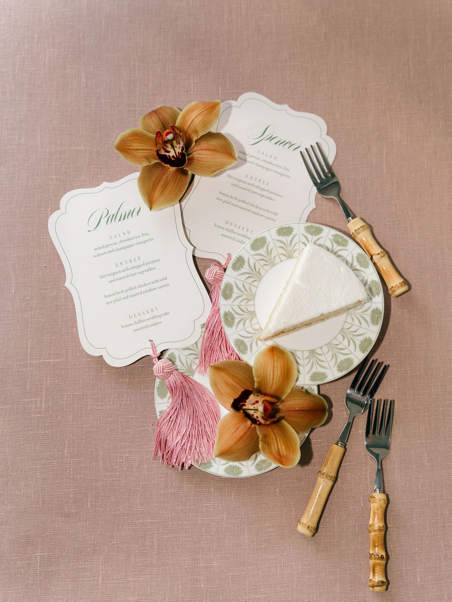 Wedding menu cards decorated with golden orchids and vintage-style cutlery.