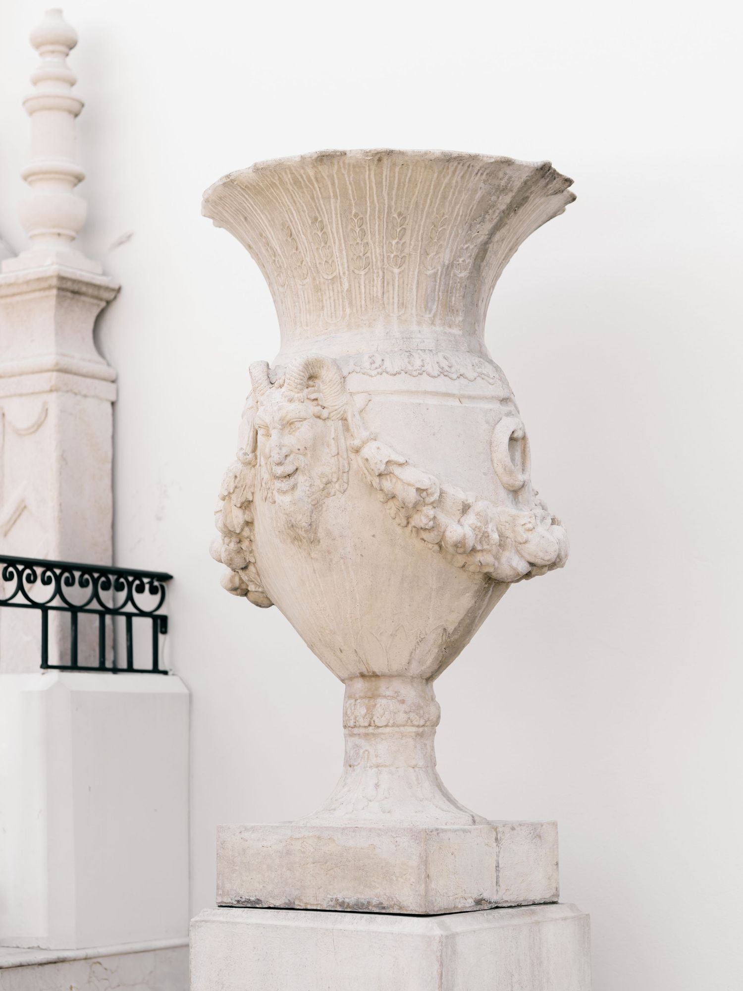 Collection of decorative white stone urns and architectural fragments displayed against a white background.