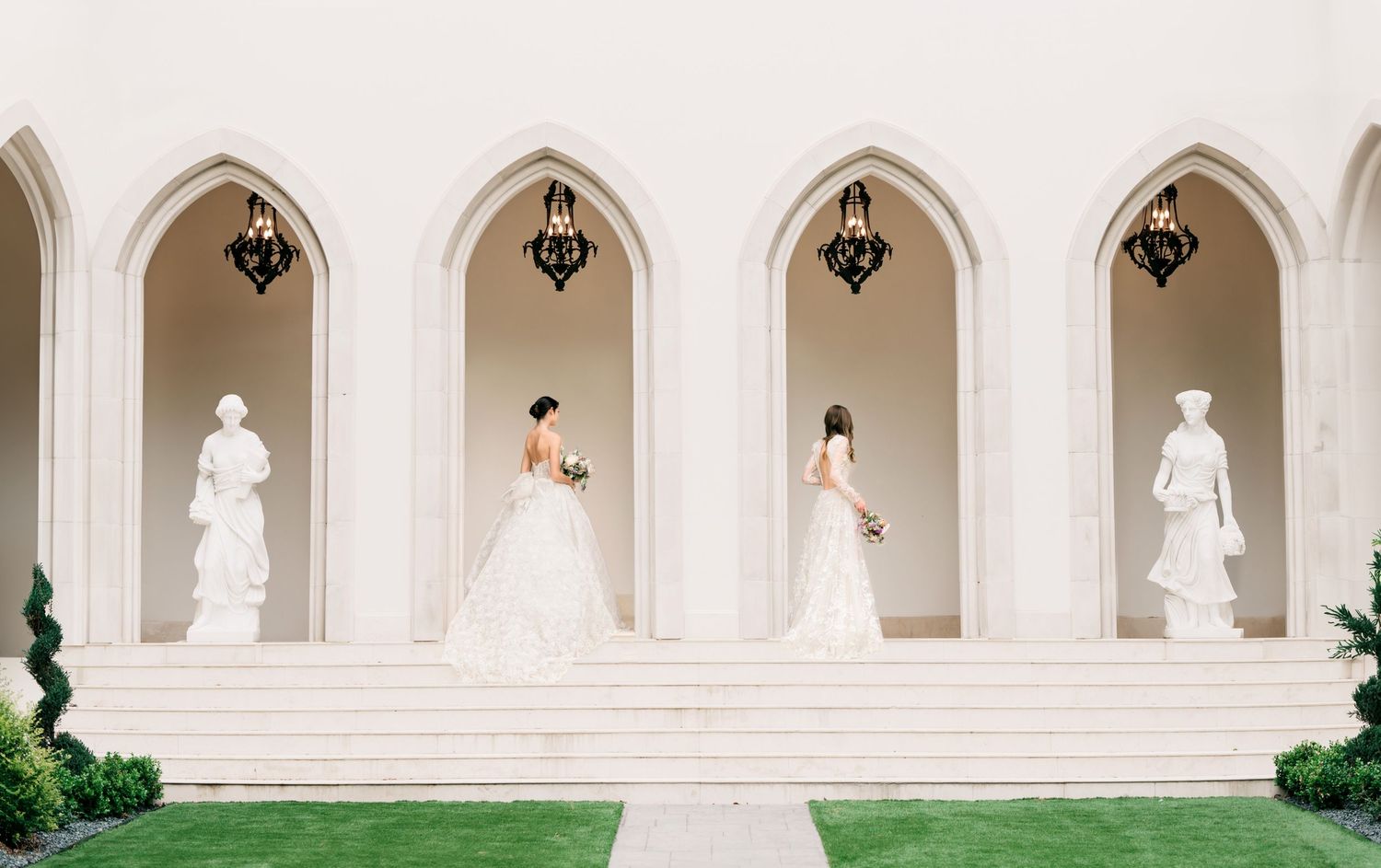 White stone colonnade with arched openings overlooking a manicured green lawn at a historic European-style building.