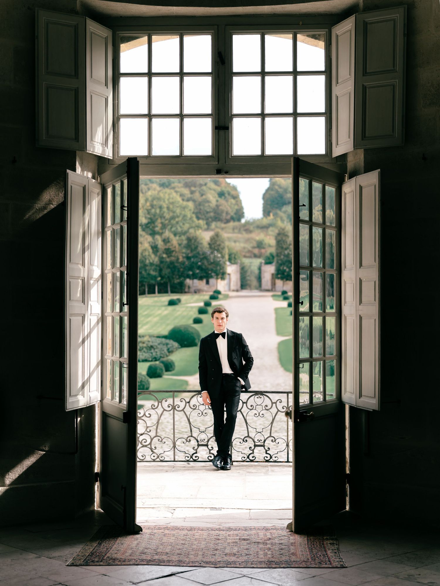 A series of three wedding photos showing a groom standing in an ornate doorway with French doors and garden view.