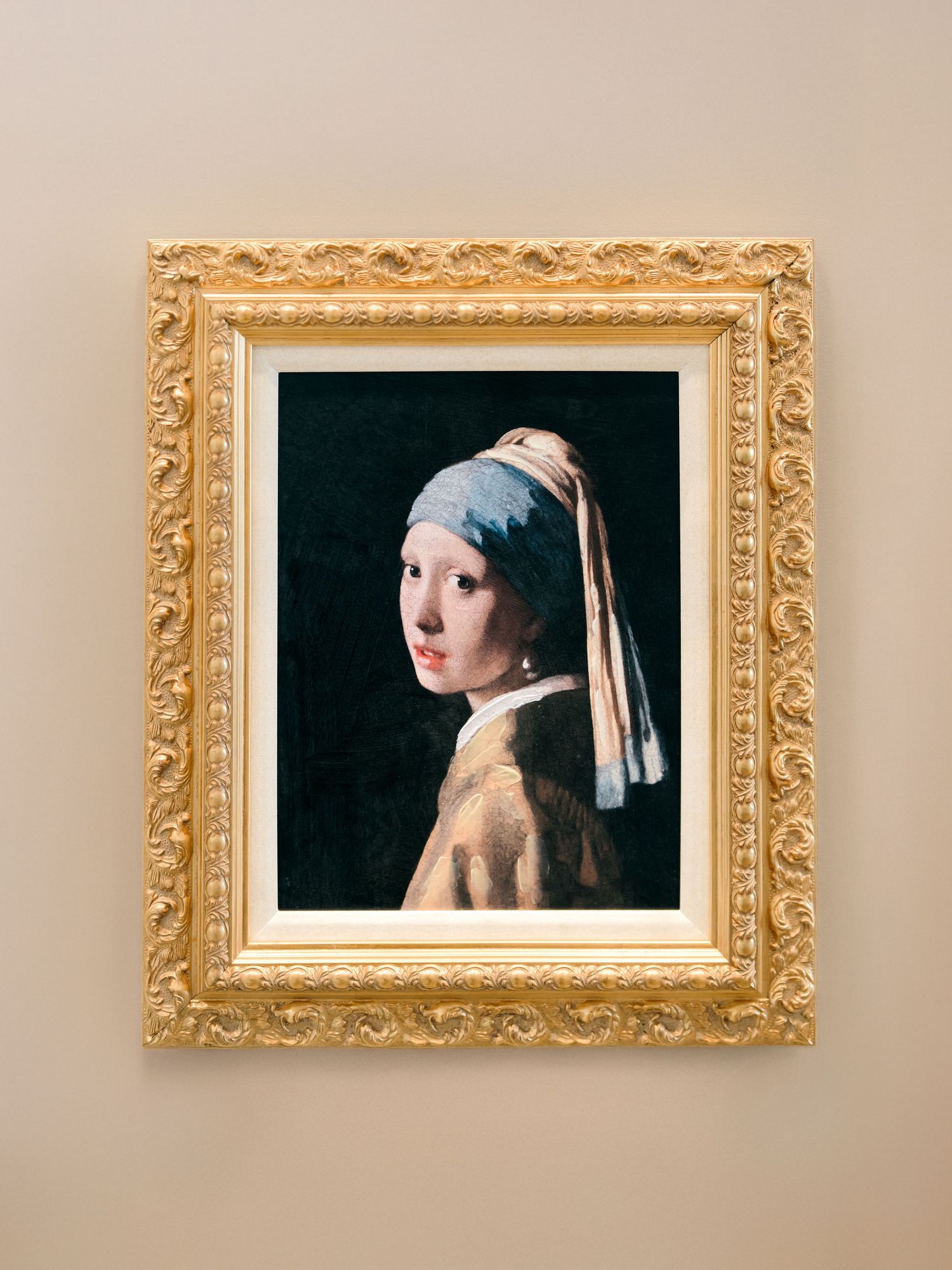 Four identical artworks in ornate gold frames hanging on a beige wall, showing a classic Dutch Golden Age painting.