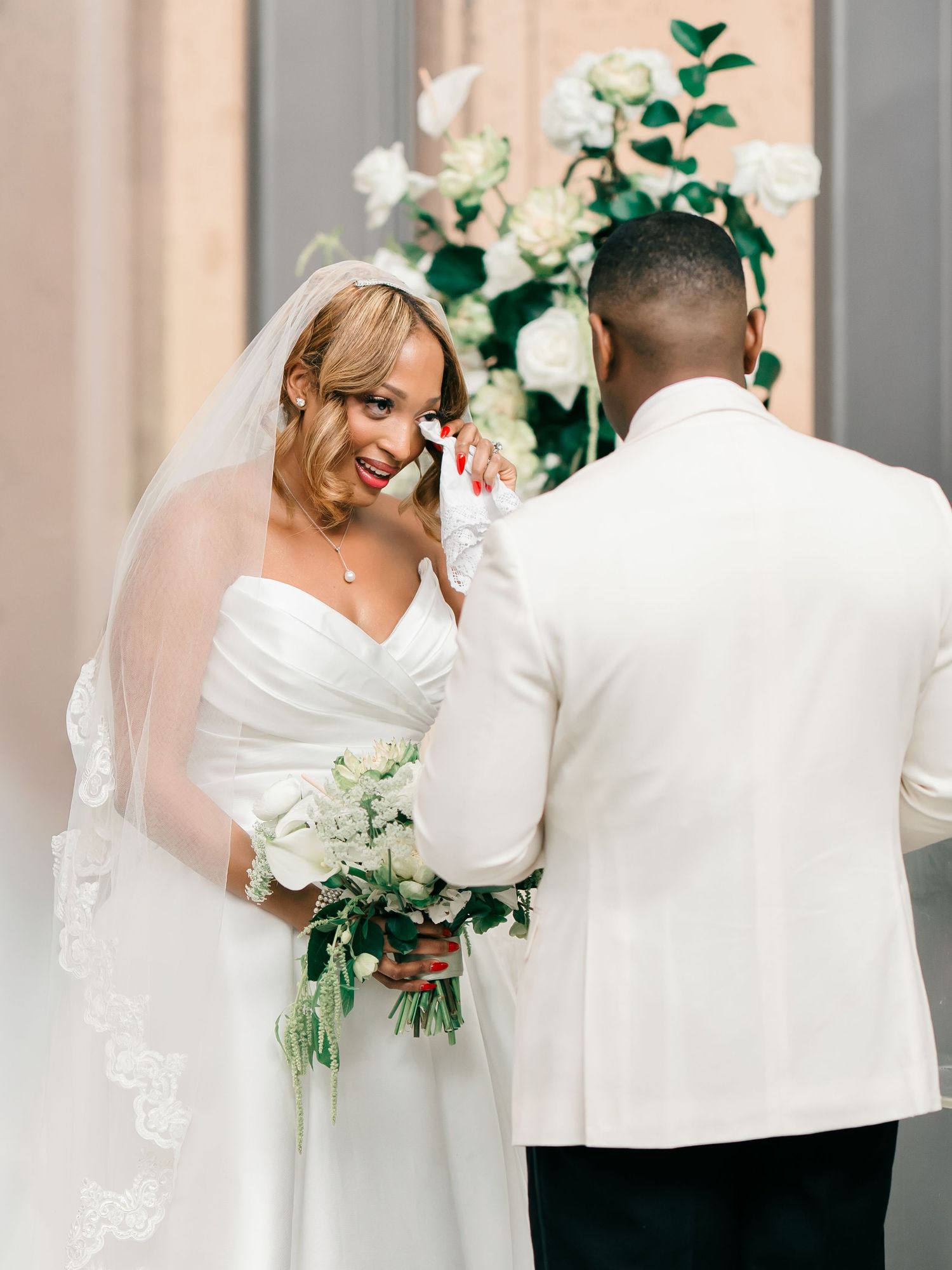 Wedding couple shares intimate moments in light filled chapel with white and green floral decorations.