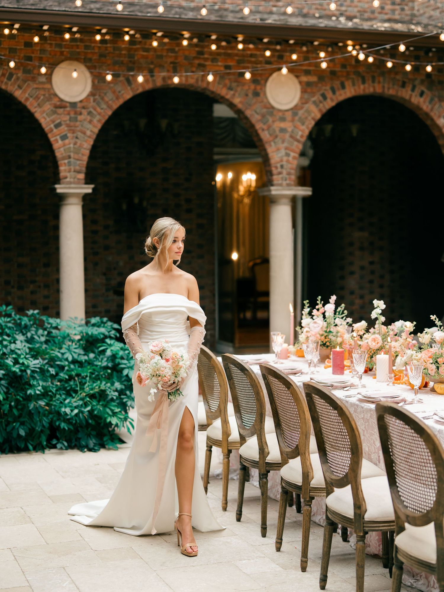 Elegant wedding reception setup with rattan chairs and floral centerpieces in a romantic courtyard venue.