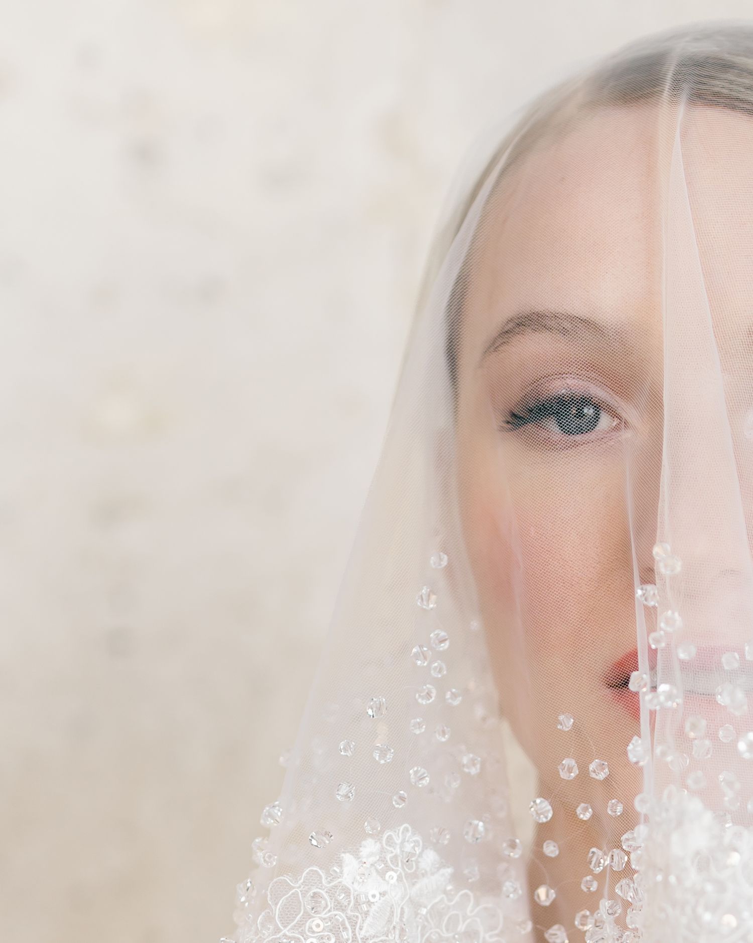 A close up detail shot of a Bride's face with her veil and red lipstick.