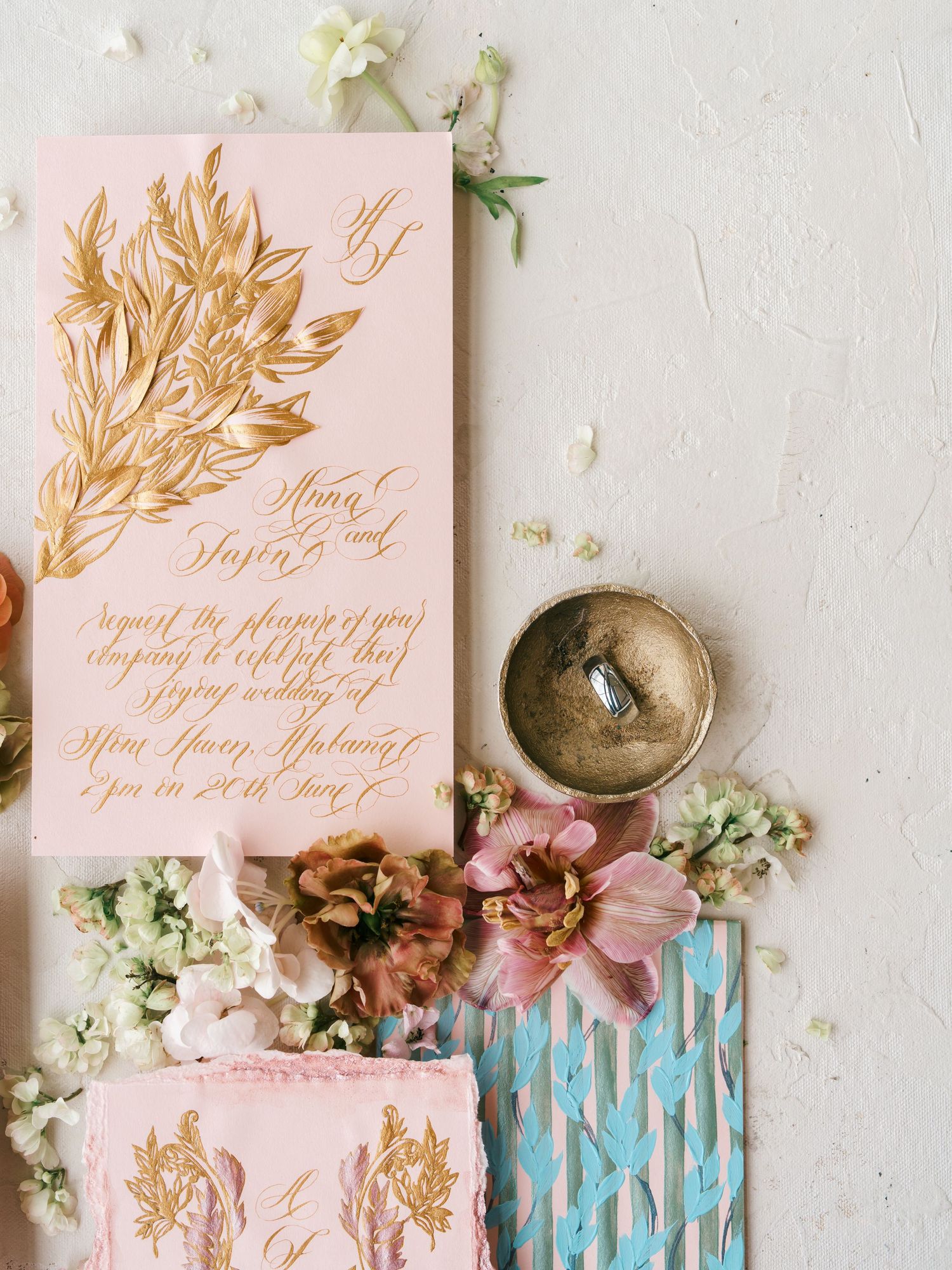 Elegant pink and gold wedding invitation suite with calligraphy surrounded by delicate florals.