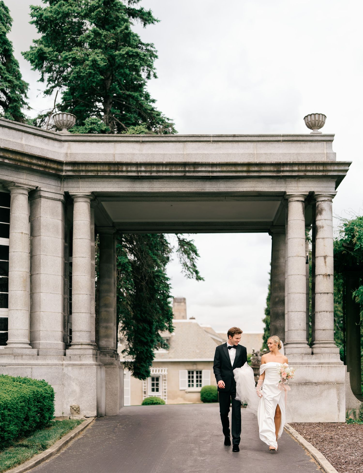 A couple walks through an elegant stone colonnade walkway in a sequence of romantic wedding photos.