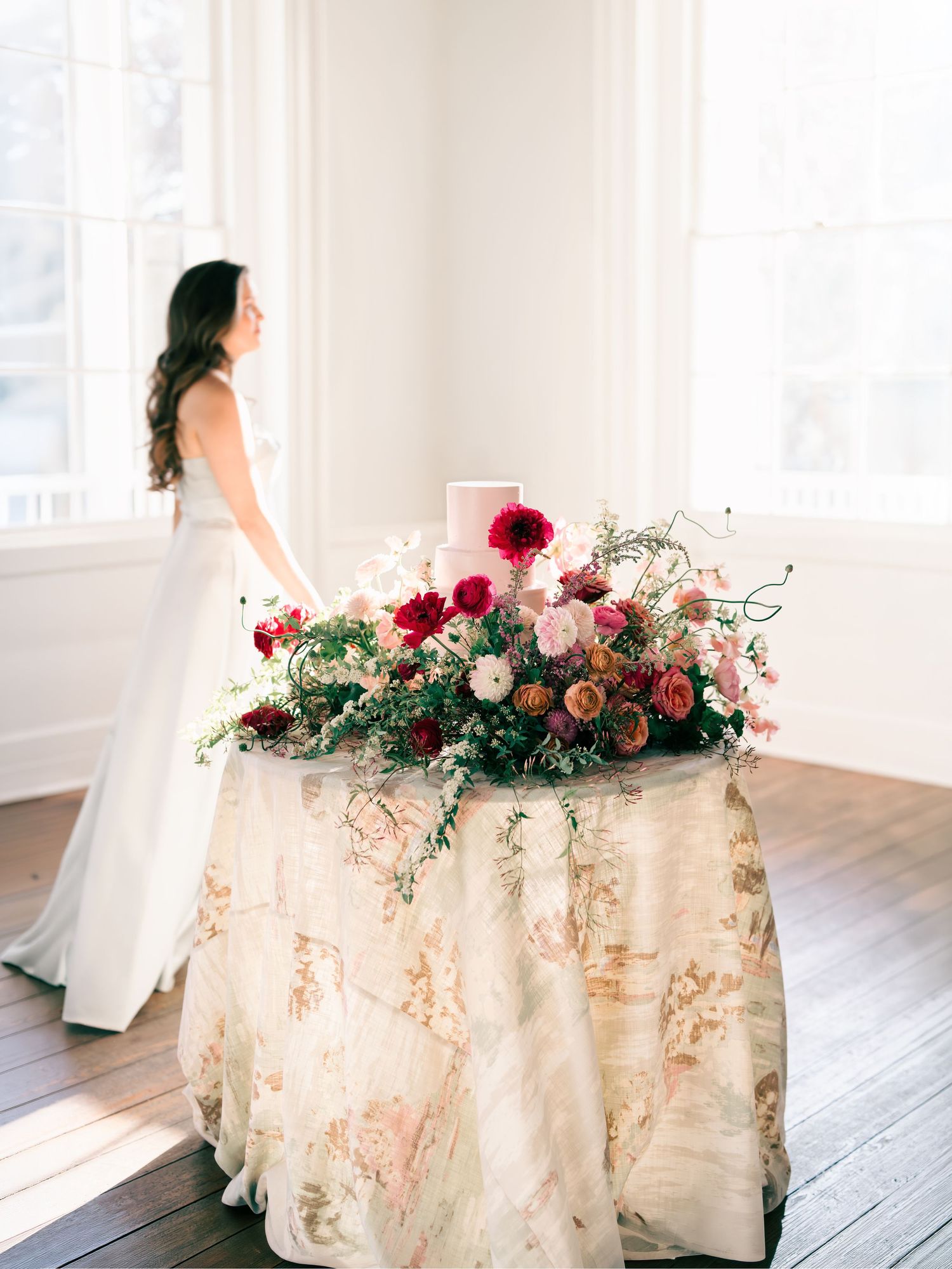 Romantic wedding table setup with delicate floral arrangements and soft white linens in a bright sunlit room.
