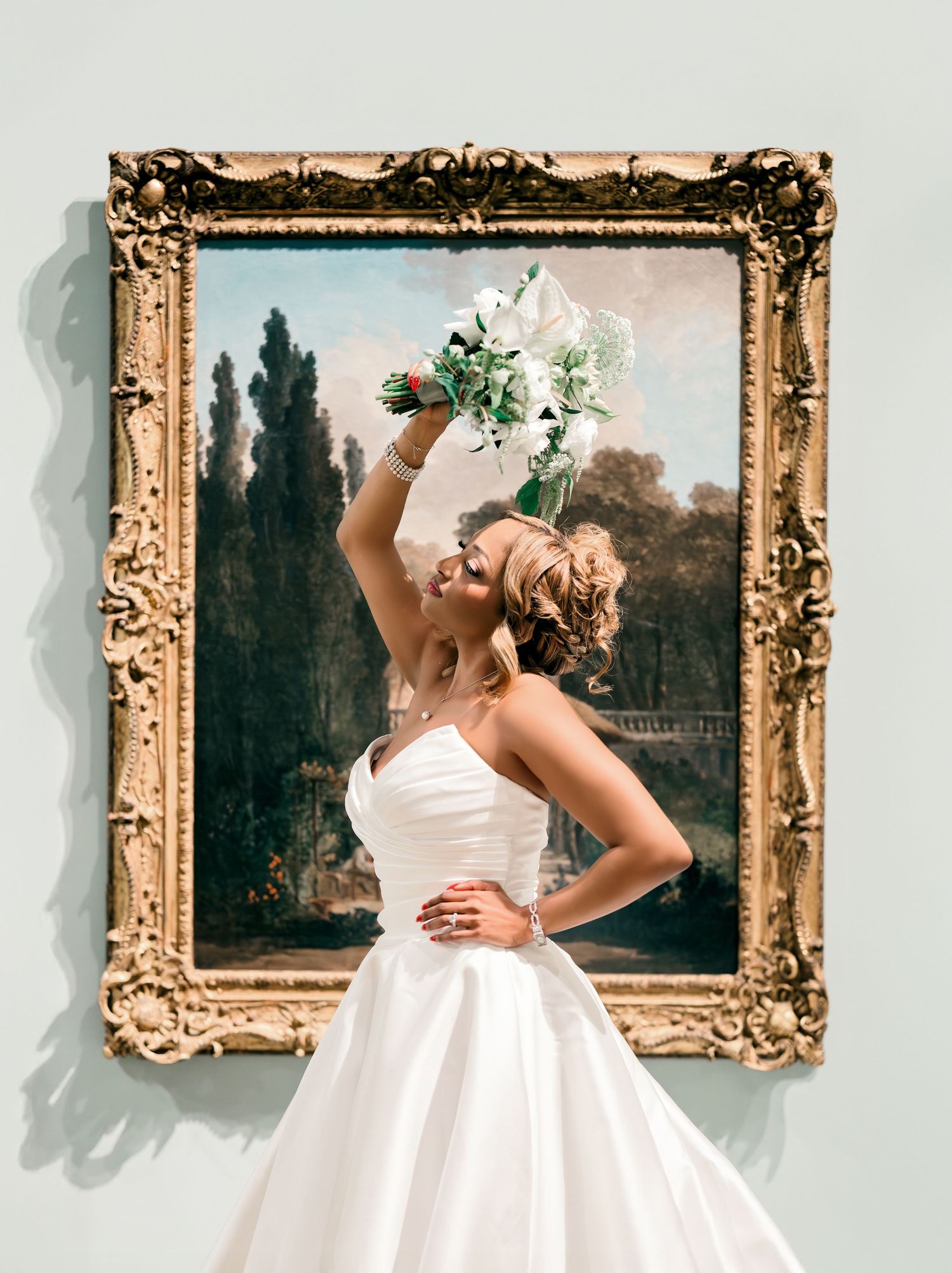 A vintage-inspired bridal portrait in a white wedding dress against an ornate gold frame with cypress trees in background.