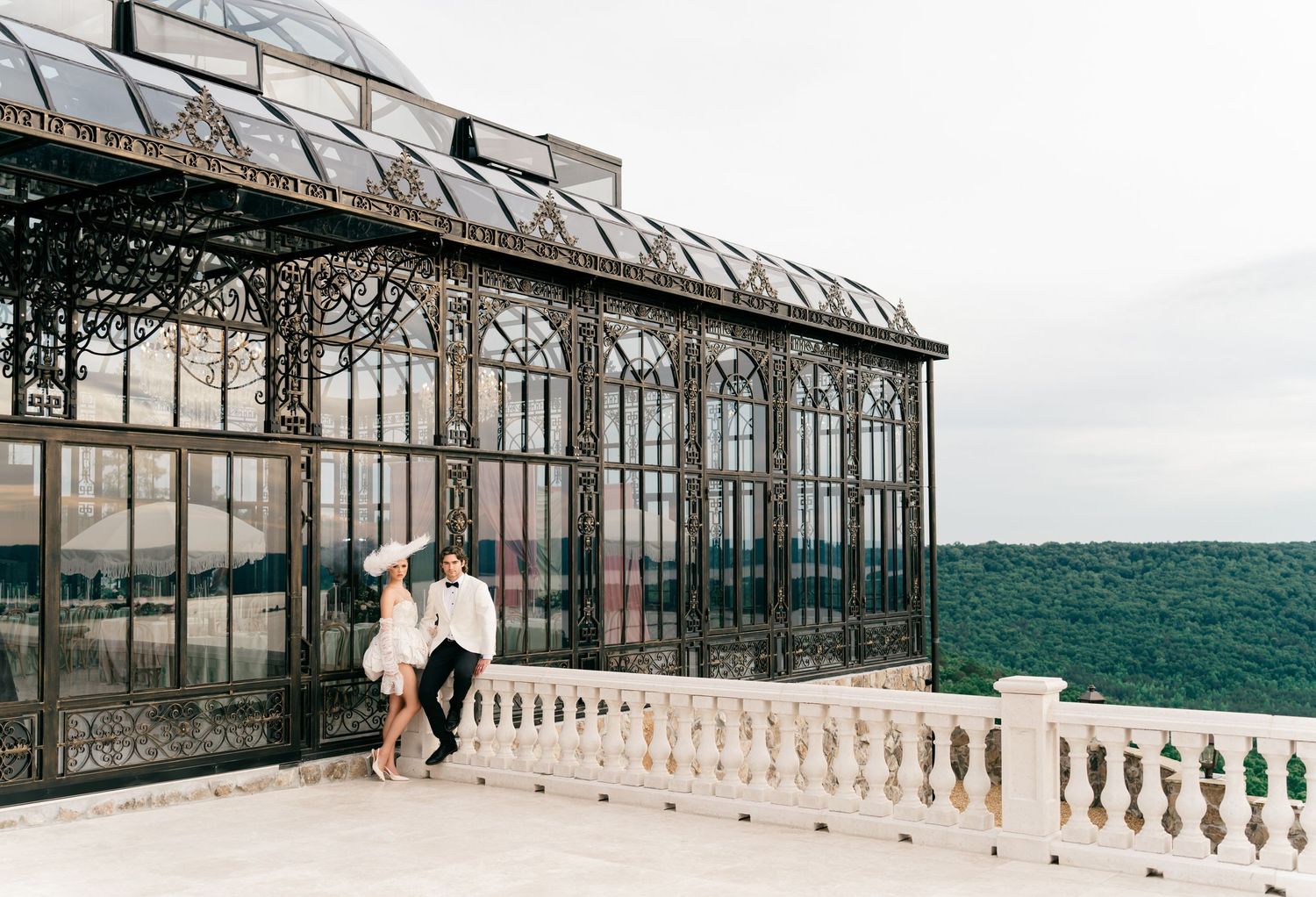 Stone Haven Wedding Venue, Alabama. Couple dancing on terrace of ornate Victorian glass greenhouse with lush green forest backdrop.