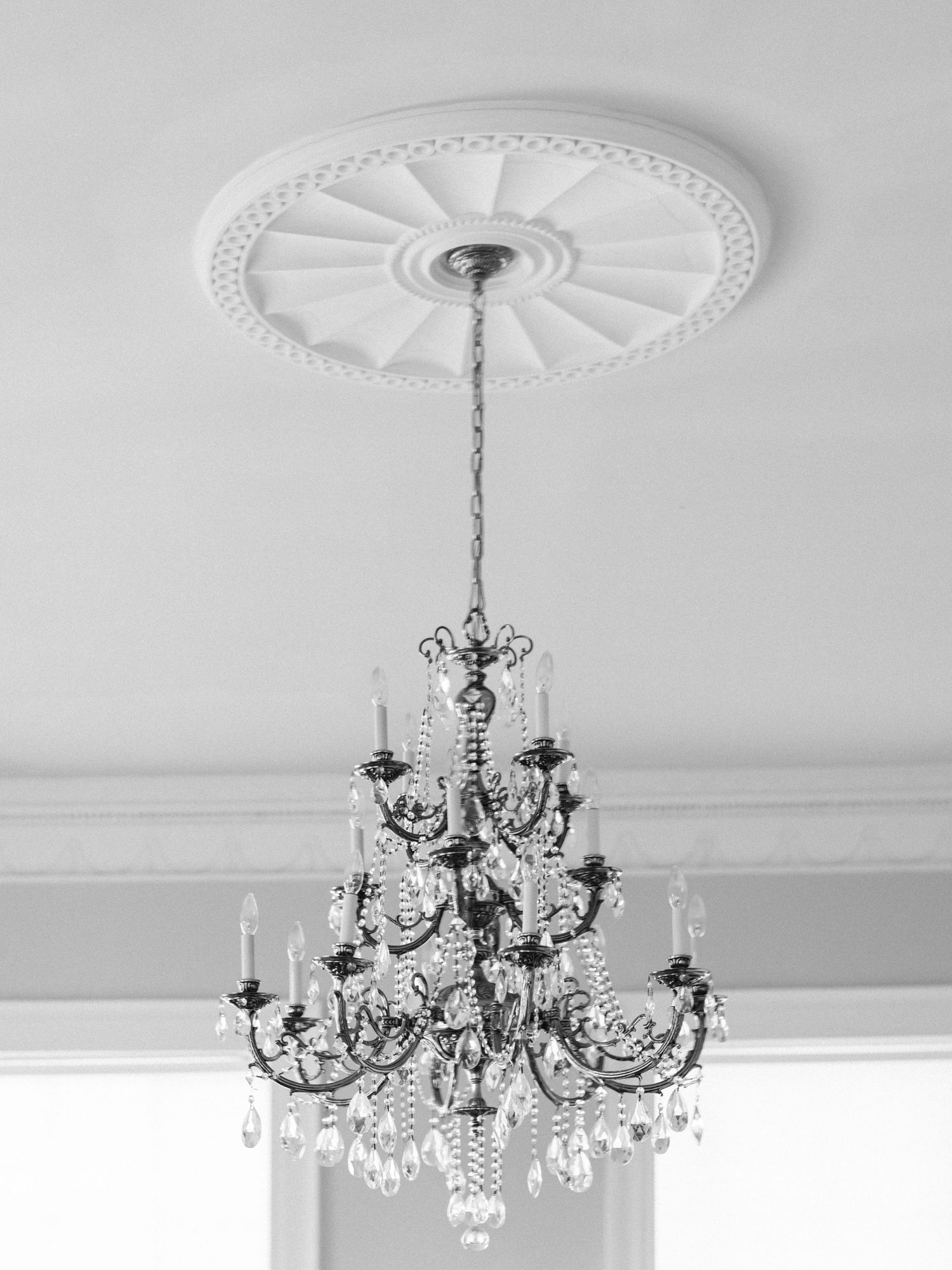 Elegant crystal chandelier hanging from an ornate white ceiling medallion.