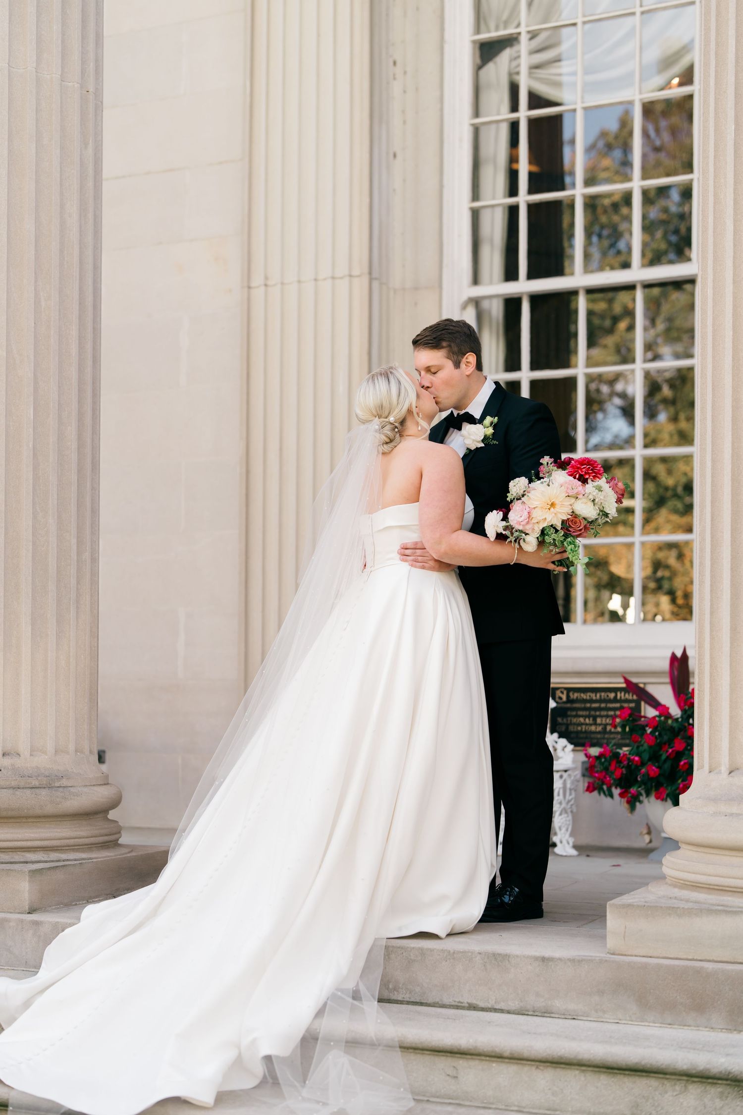 Elegant wedding couple shares romantic moments in front of a grand columned building with classic architecture.