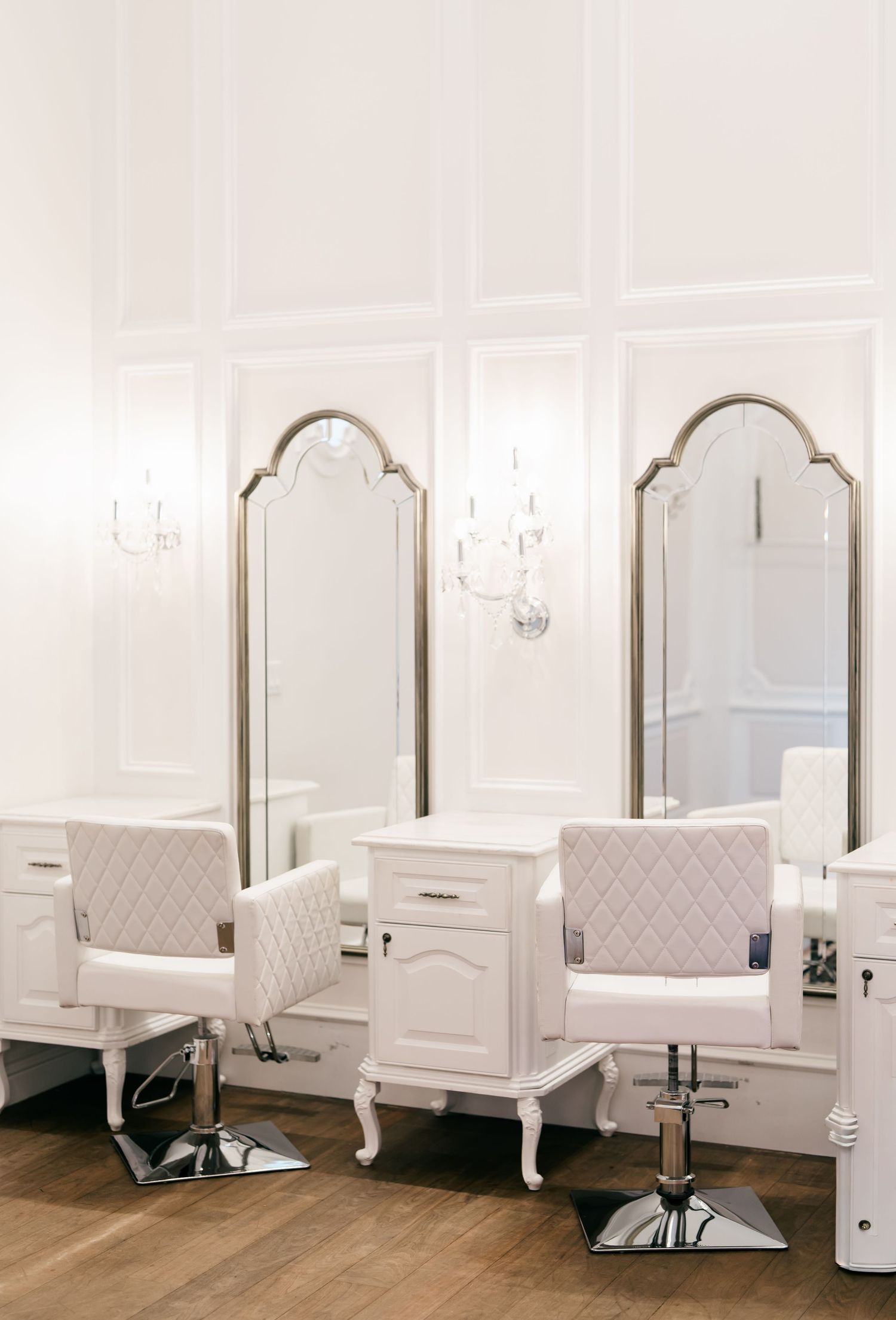 Row of elegant white vanity stations with arched mirrors in a bridal salon setting.