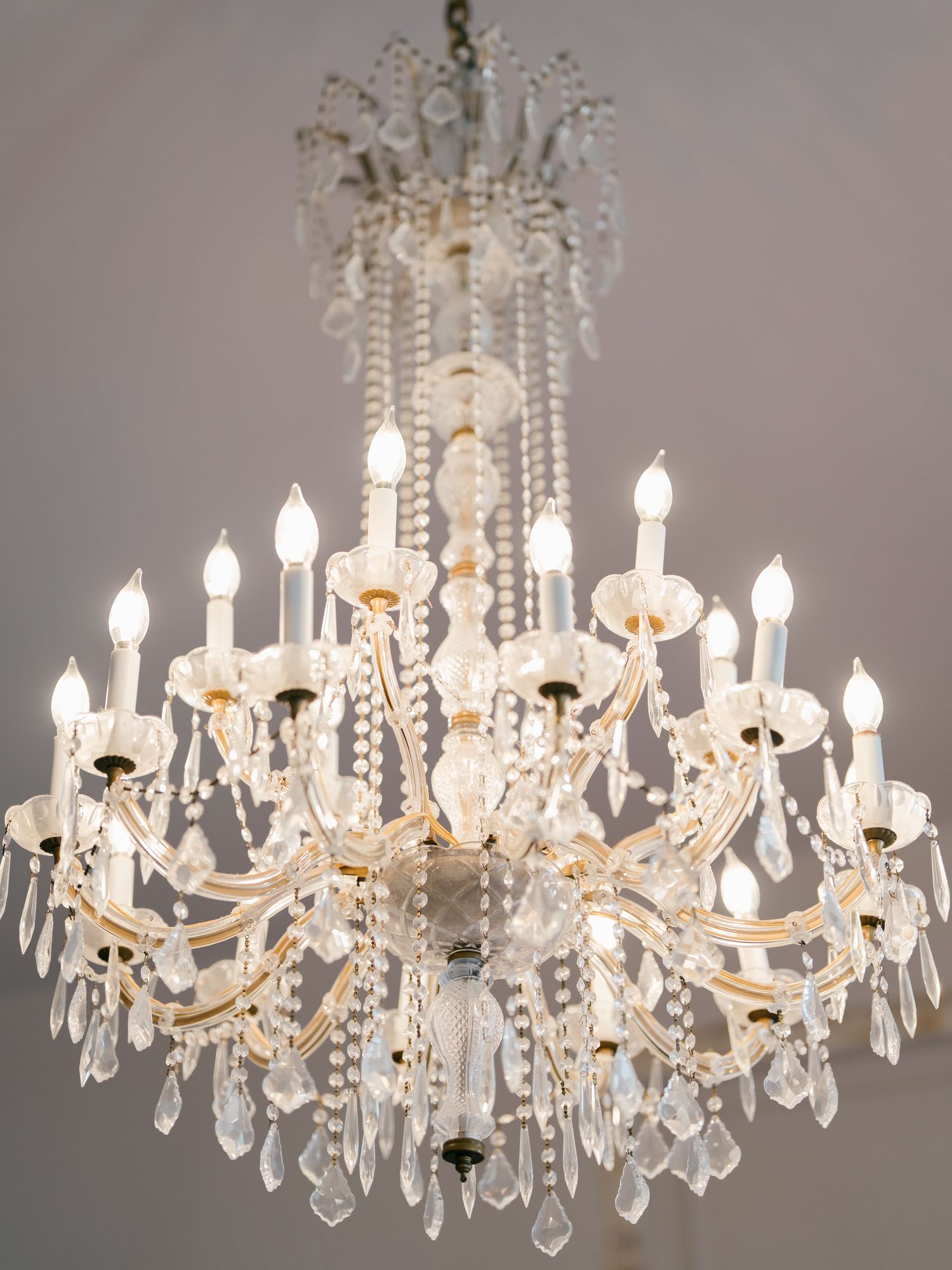 Crystal chandelier with multiple tiers of sparkling prisms and white candle-style lights.