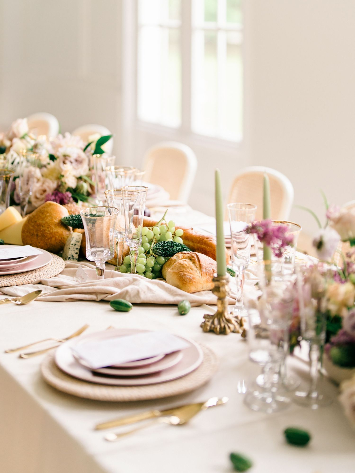 Elegant table setting with pink floral centerpieces, crystal glassware, and white china plates.