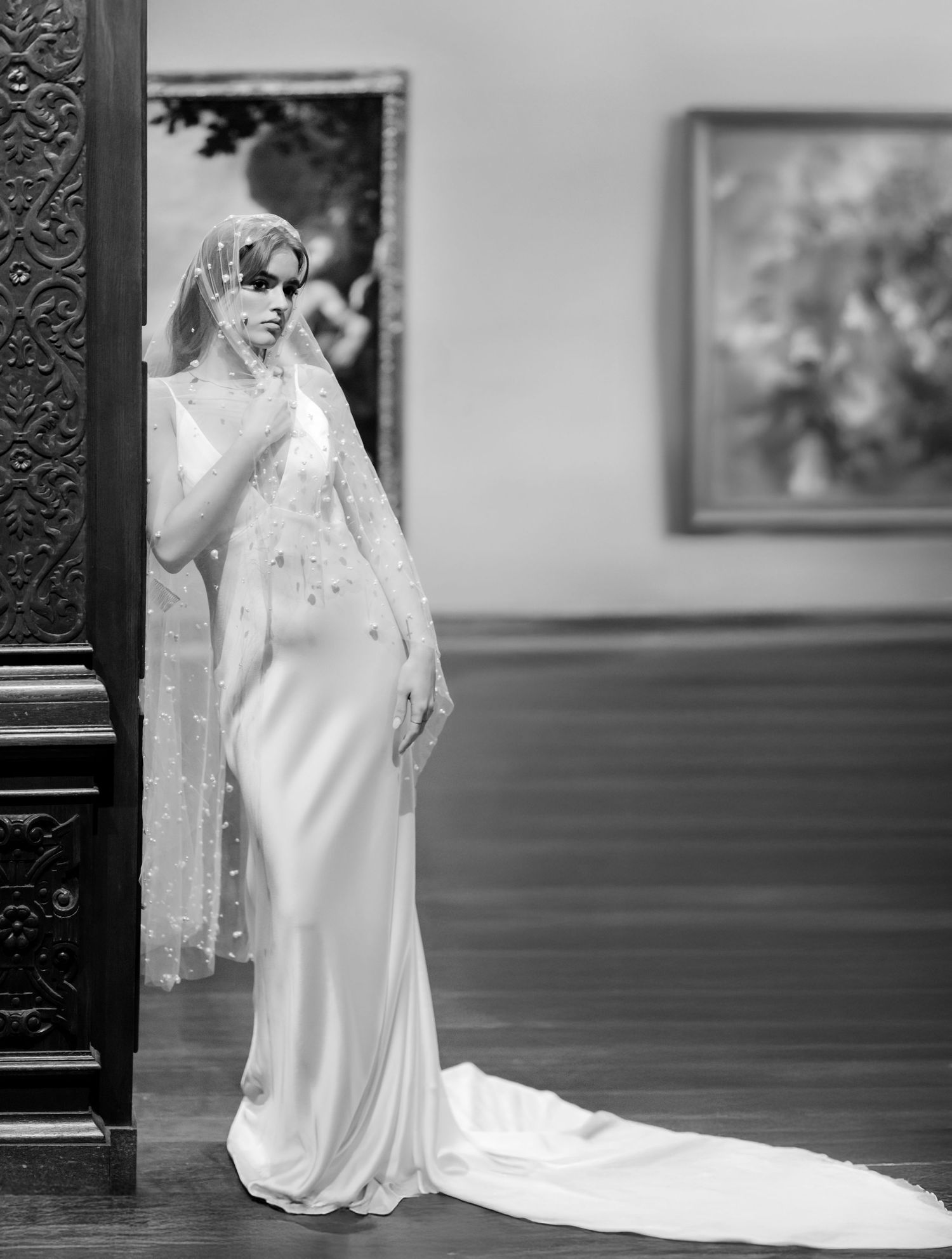 A vintage black and white wedding photograph showing a bridal gown with elegant train and flowing veil details.