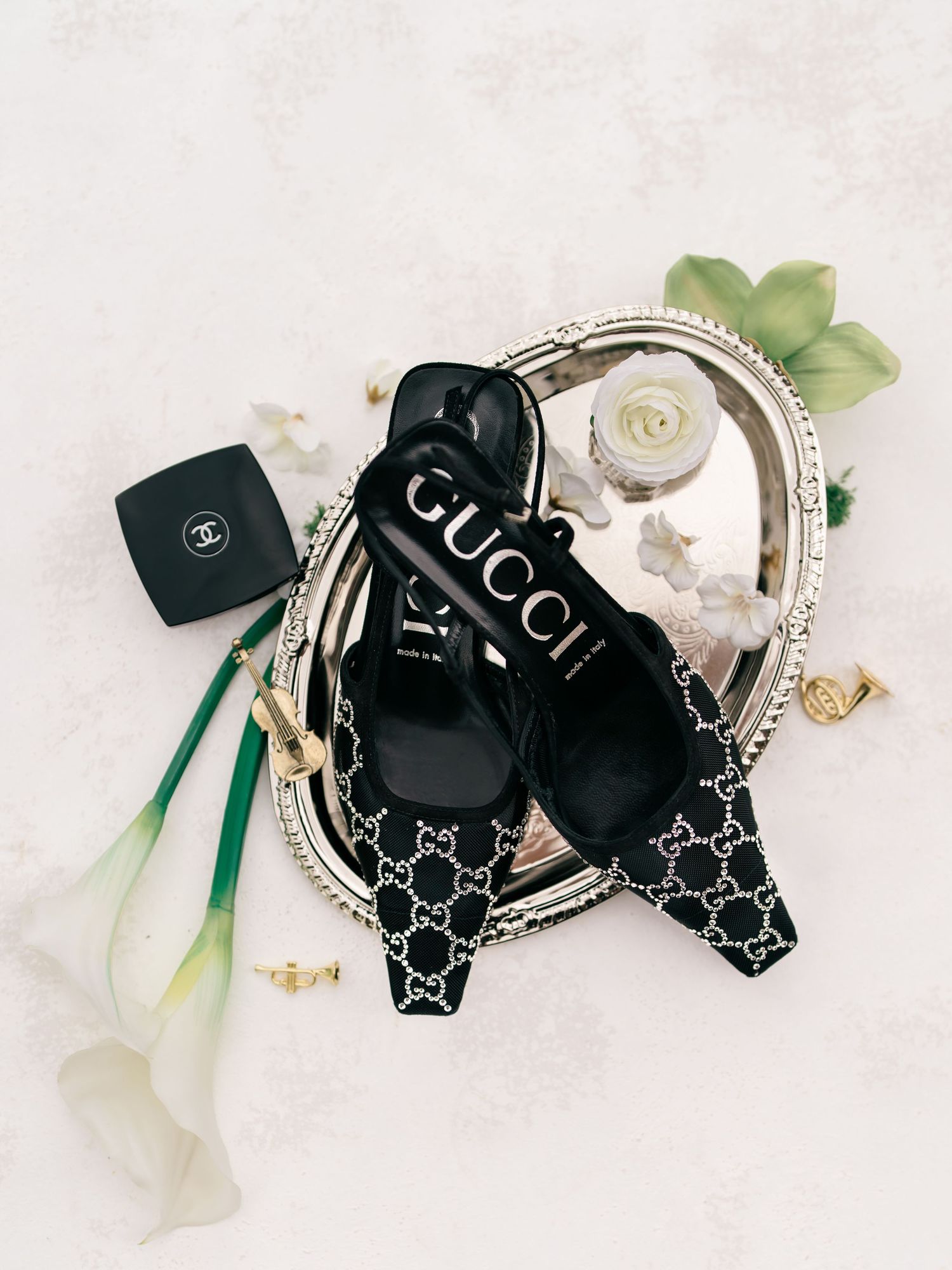 Black Gucci GG canvas pattern bow hair accessories with white ribbons and crystal embellishments displayed on white surface.