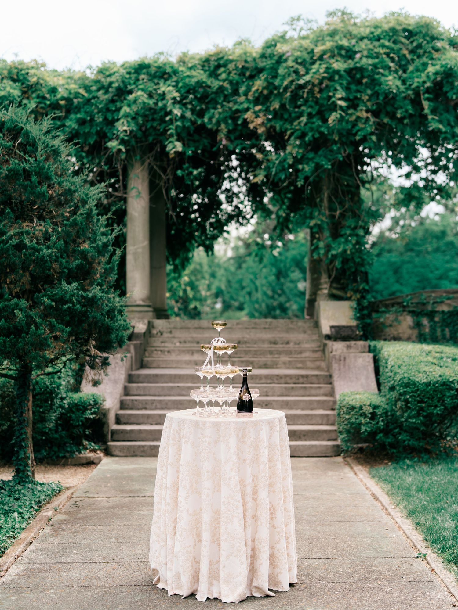 A series of outdoor stone steps with elegant white tables and greenery creating a romantic garden setting.