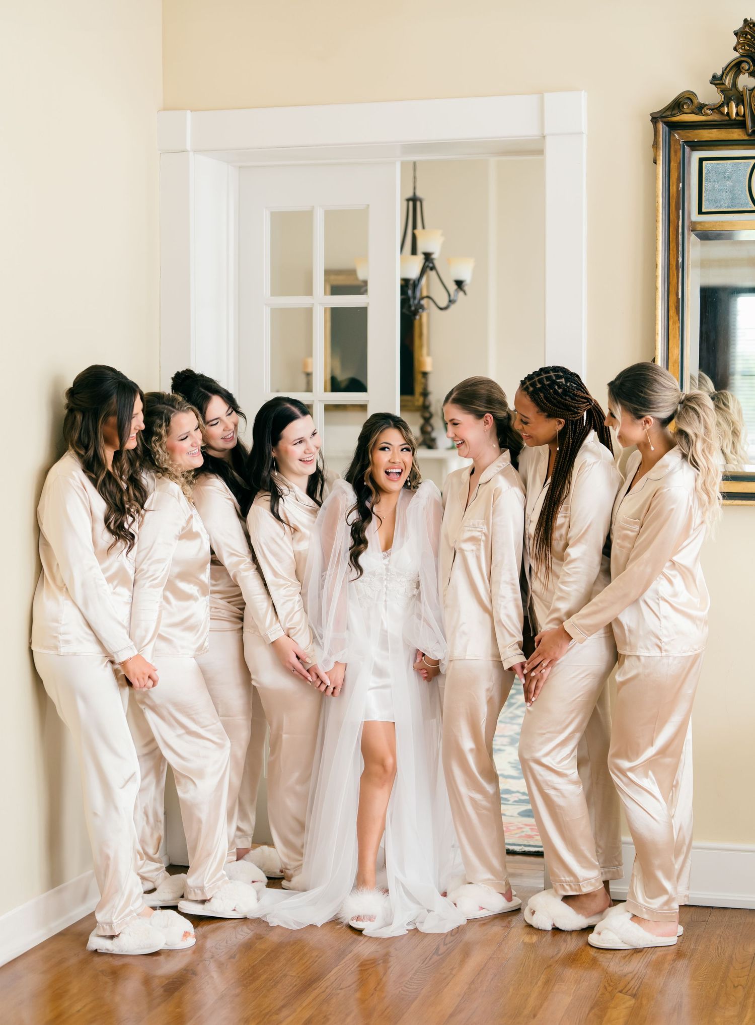 A group in matching cream-colored loungewear and robes sits lined up against a white wall in a candid moment.