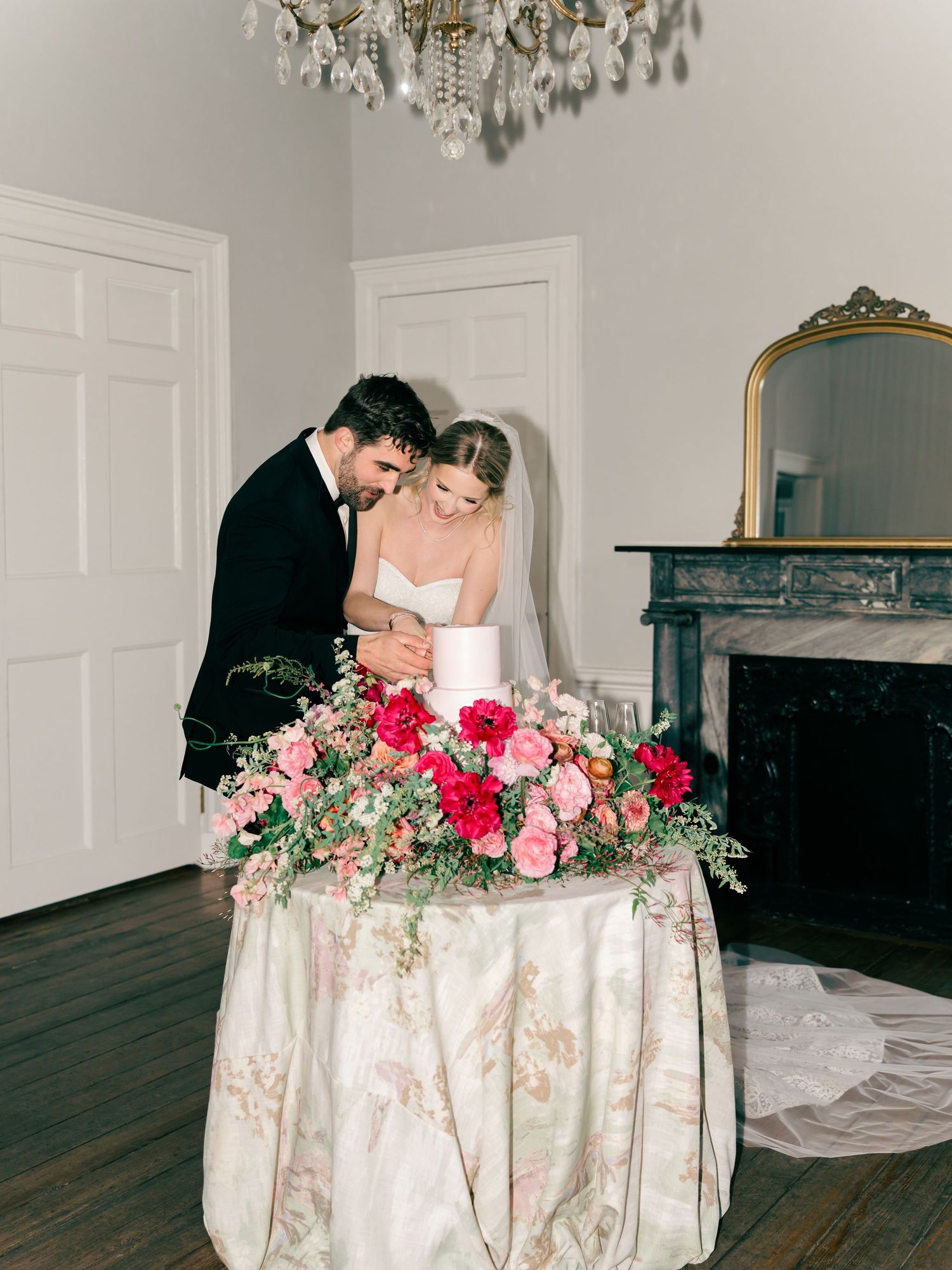 Wedding couple shares intimate moment at reception table decorated with pink roses and vintage decor.