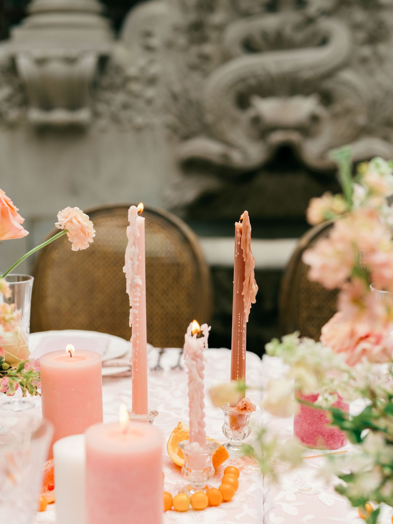 Pink candles and delicate floral arrangements create an elegant tablescape with soft peach and coral tones.