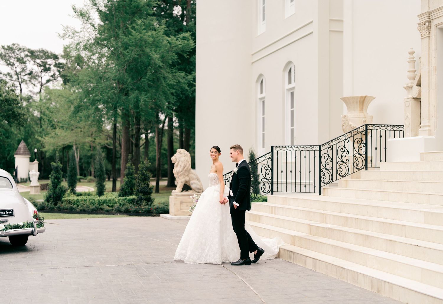 A wedding couple and their photographer capture romantic moments on elegant white mansion steps.