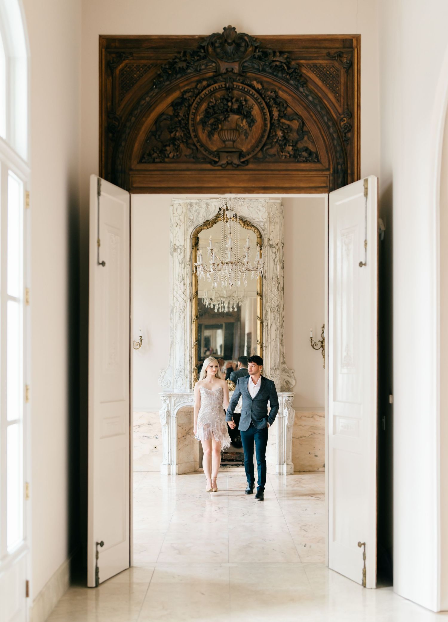 A panoramic triptych of an elegant couple walking through a grand white palace hallway with ornate ceiling details.