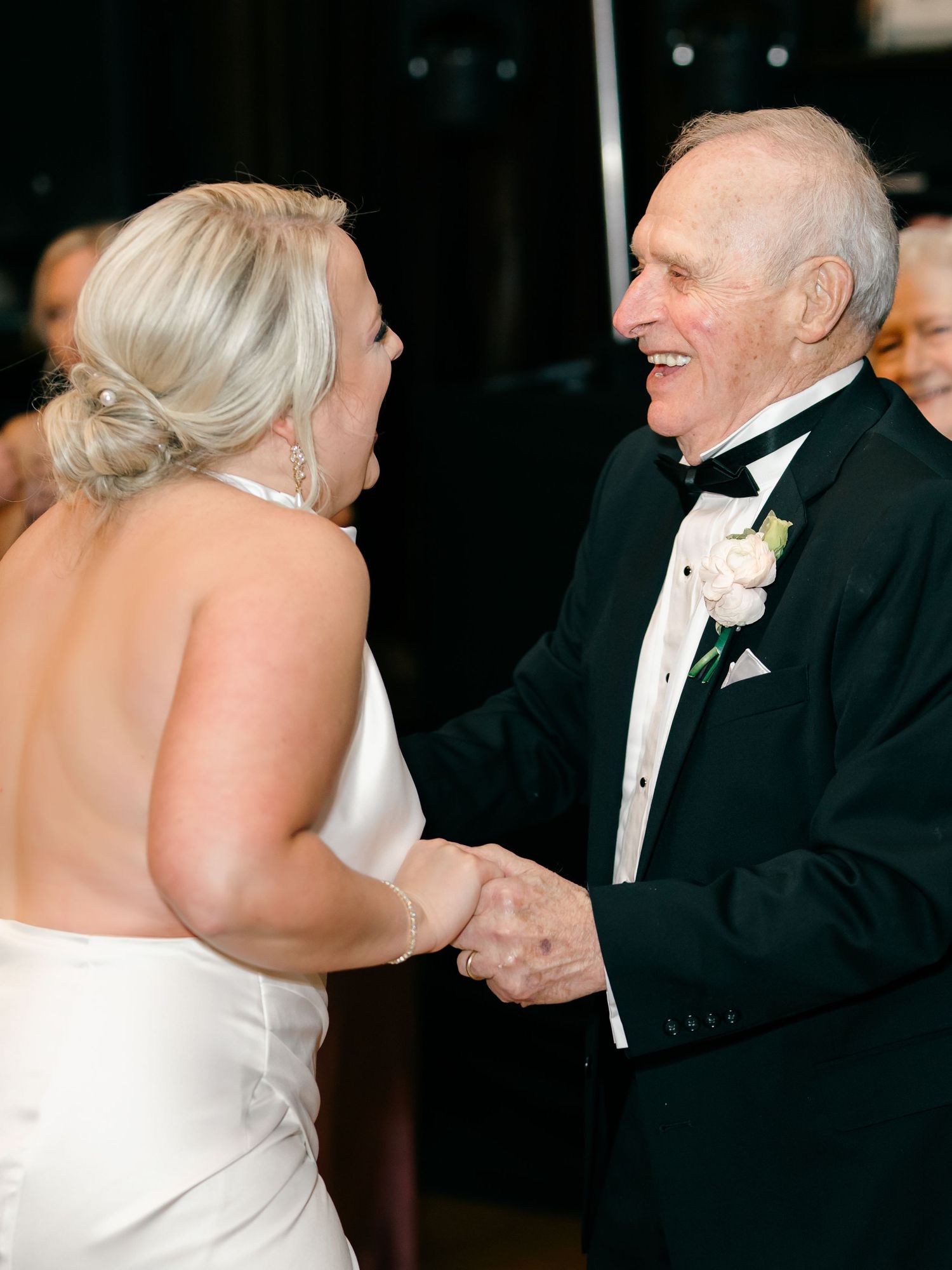 A couple in formal attire dancing together at an elegant event, with the bride in white and groom in a tuxedo.