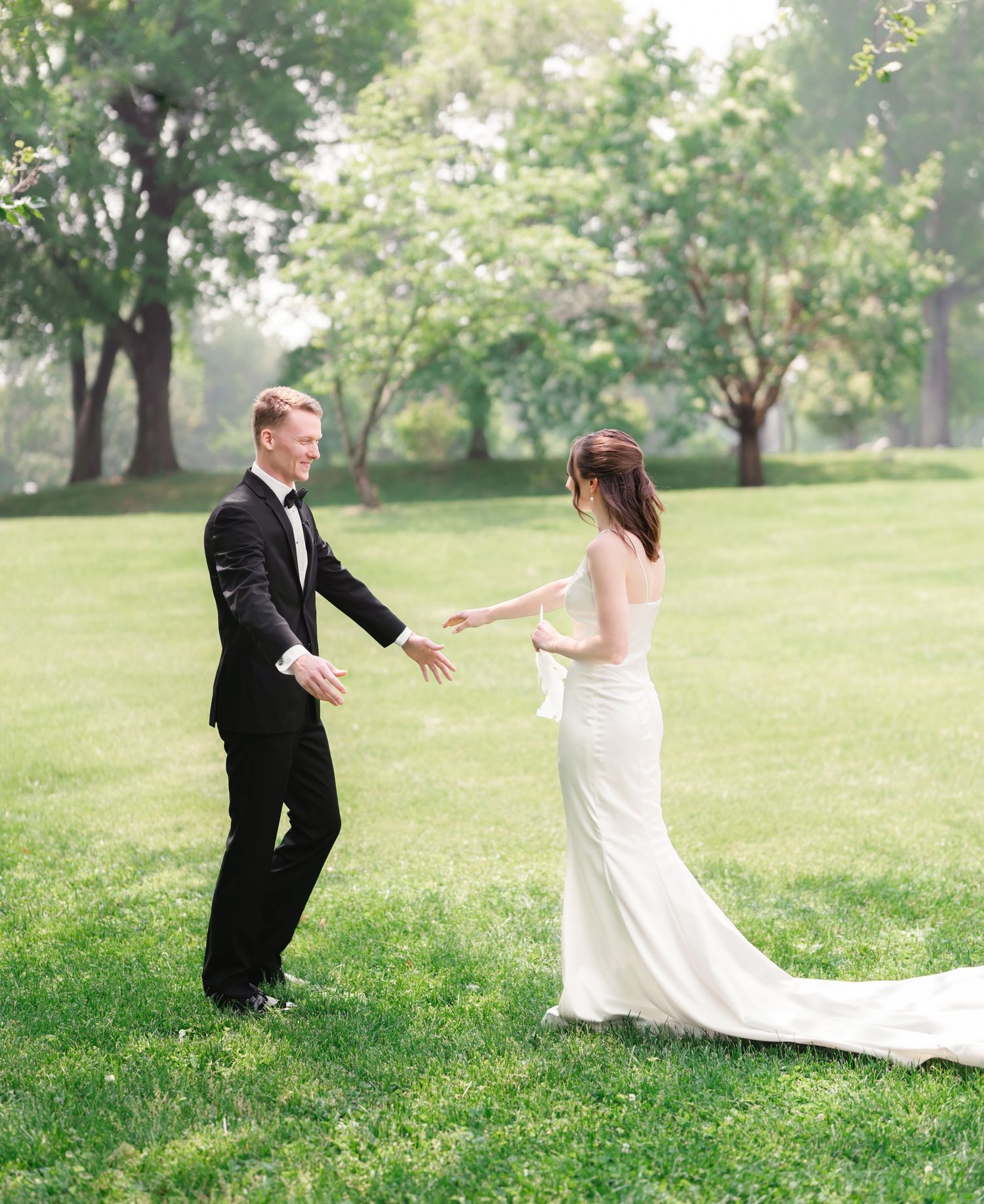 Joyful wedding couple dancing on a lush green lawn during springtime.