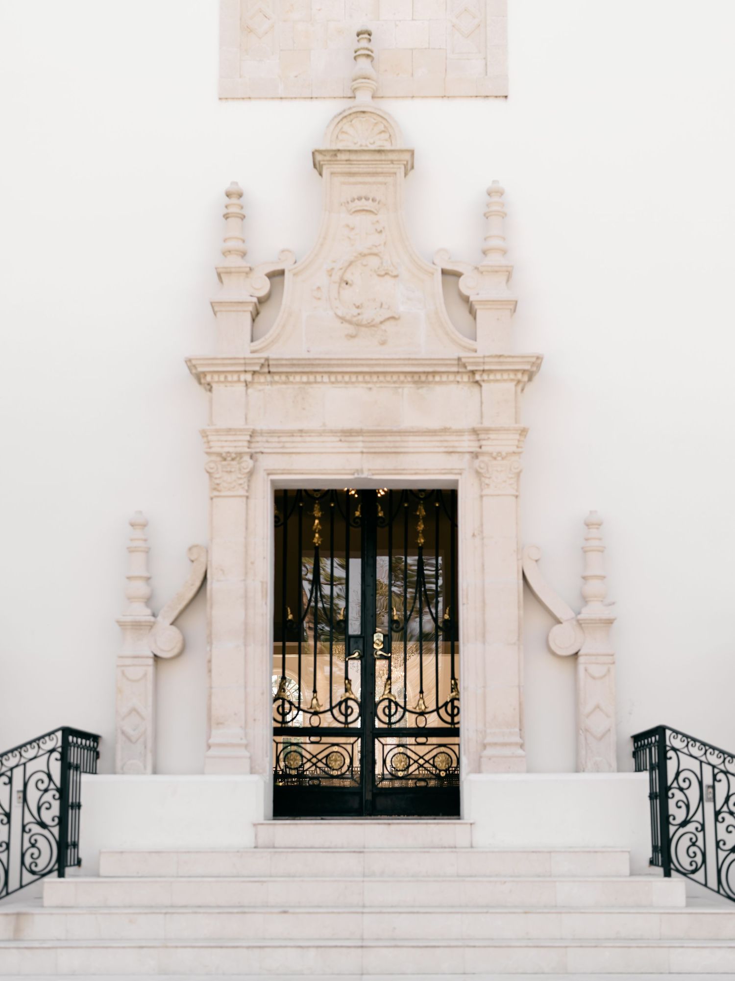 Ornate white Spanish colonial architectural details with wrought iron window grates on a pristine stucco facade.