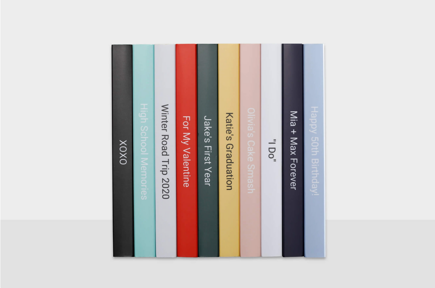 Row of colorful hardcover books standing vertically on white surface arranged by rainbow spectrum.