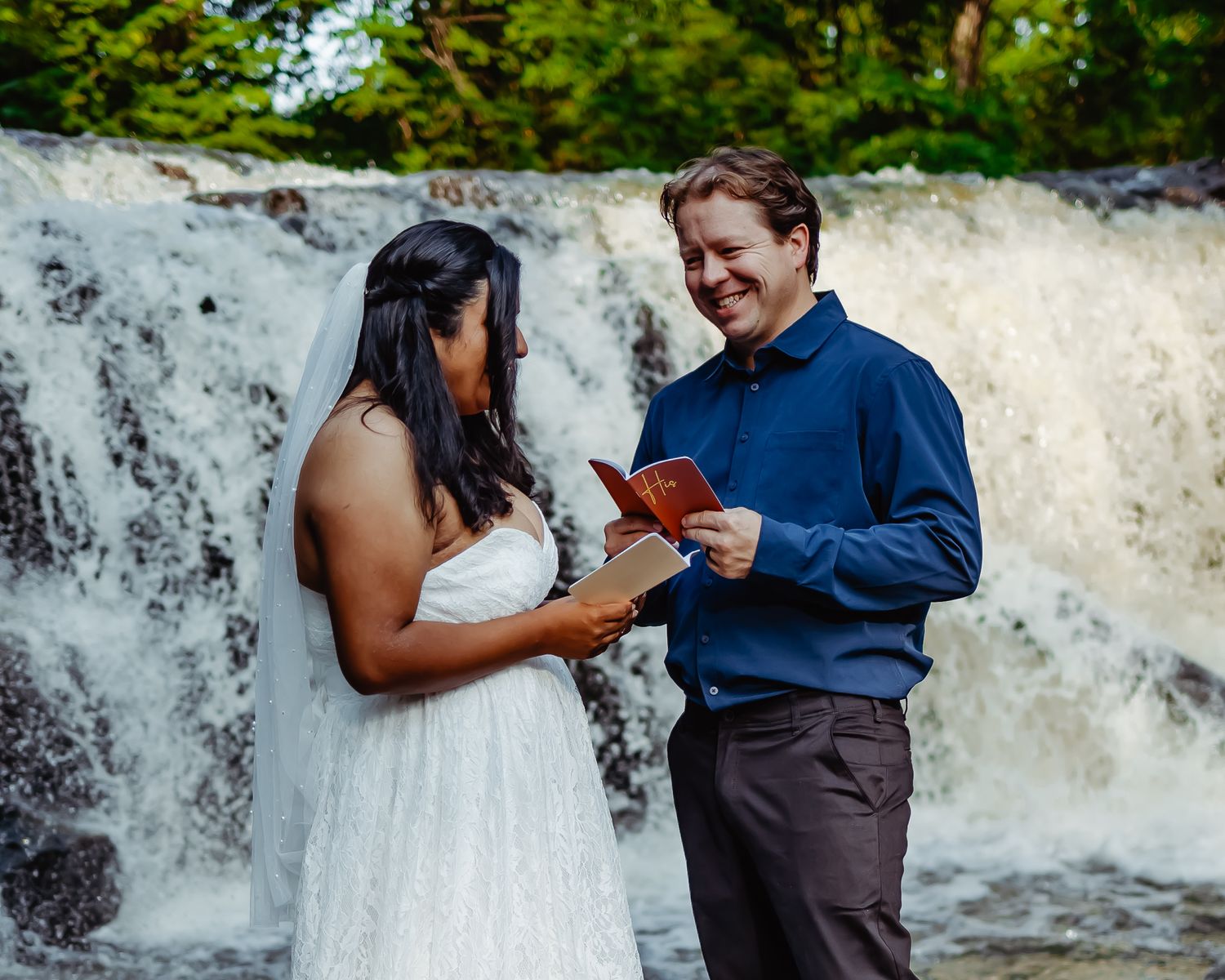 Couple exchanges vows in front of a majestic waterfall during outdoor ceremony.