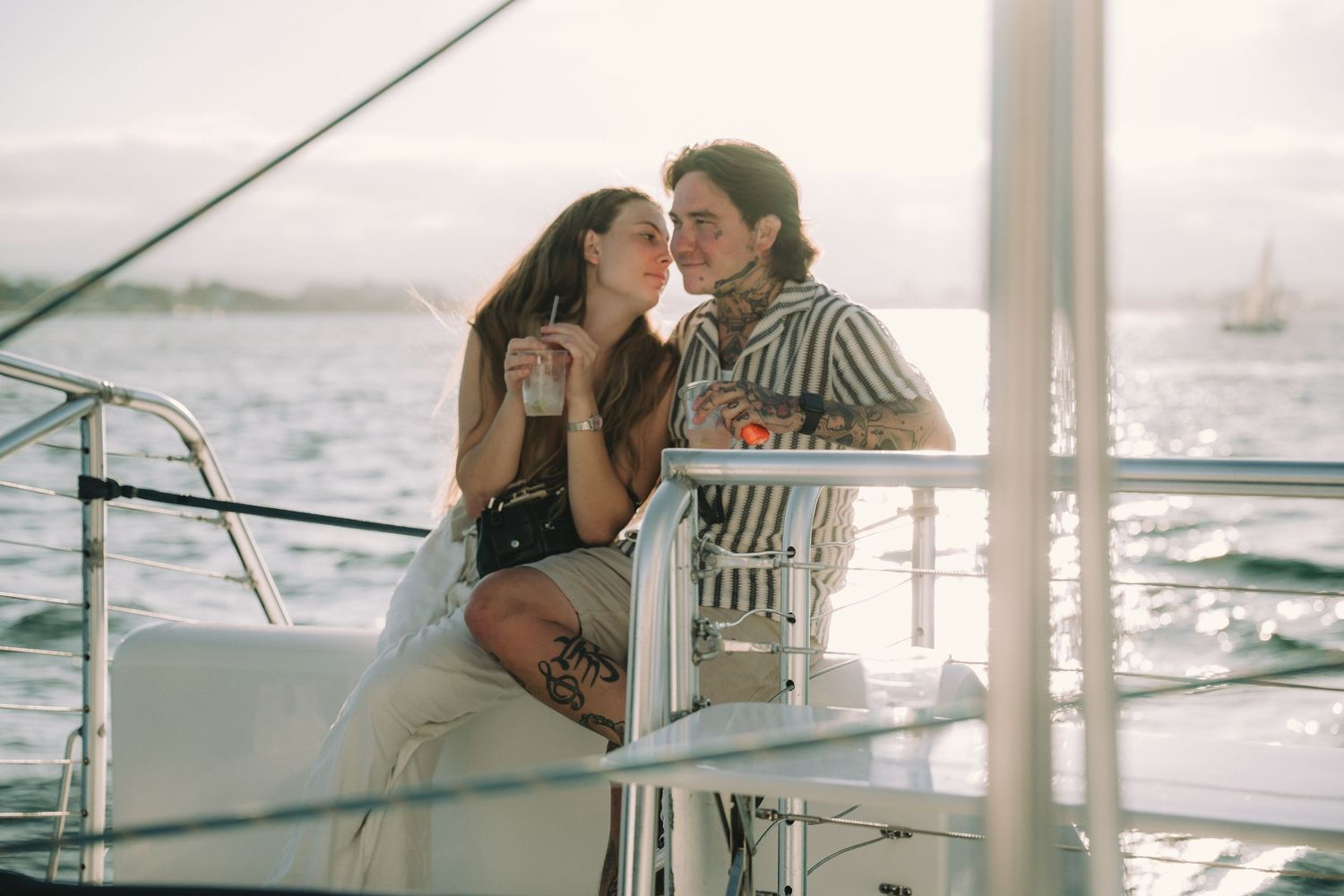 Romantic couple sharing a tender moment on a luxury sailboat at sunset on calm ocean waters.