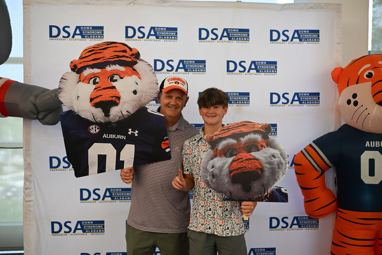 Two people pose with Auburn University tiger mascots at a DSA event backdrop.