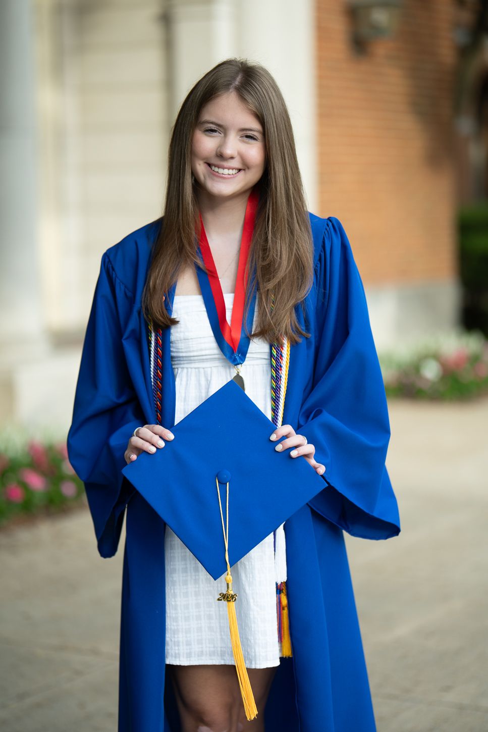 Smiling girl in blue graduation gown  holding her cap.