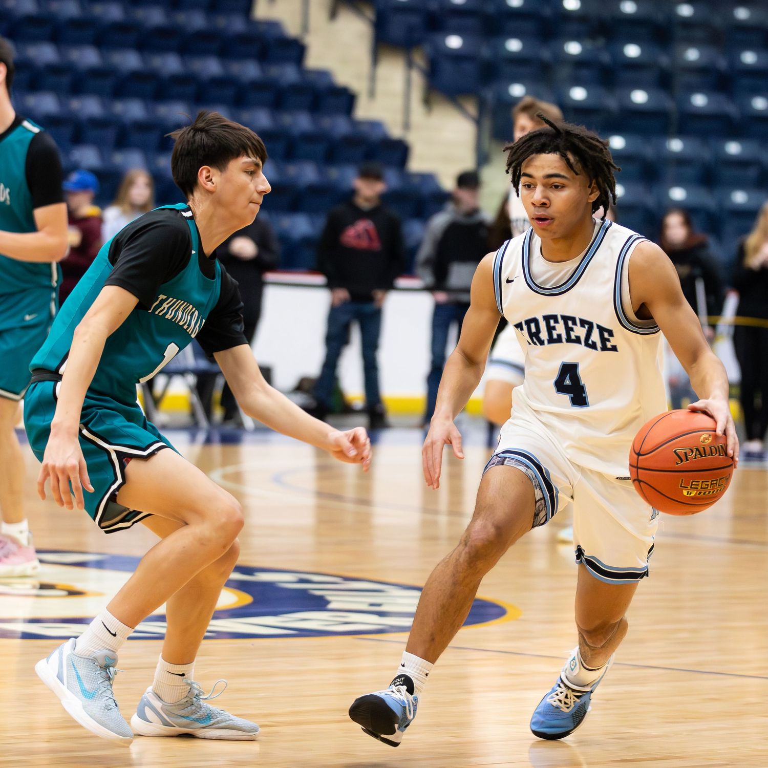 Breeze player #4 dribbles past teal-uniformed defender during high school basketball game.