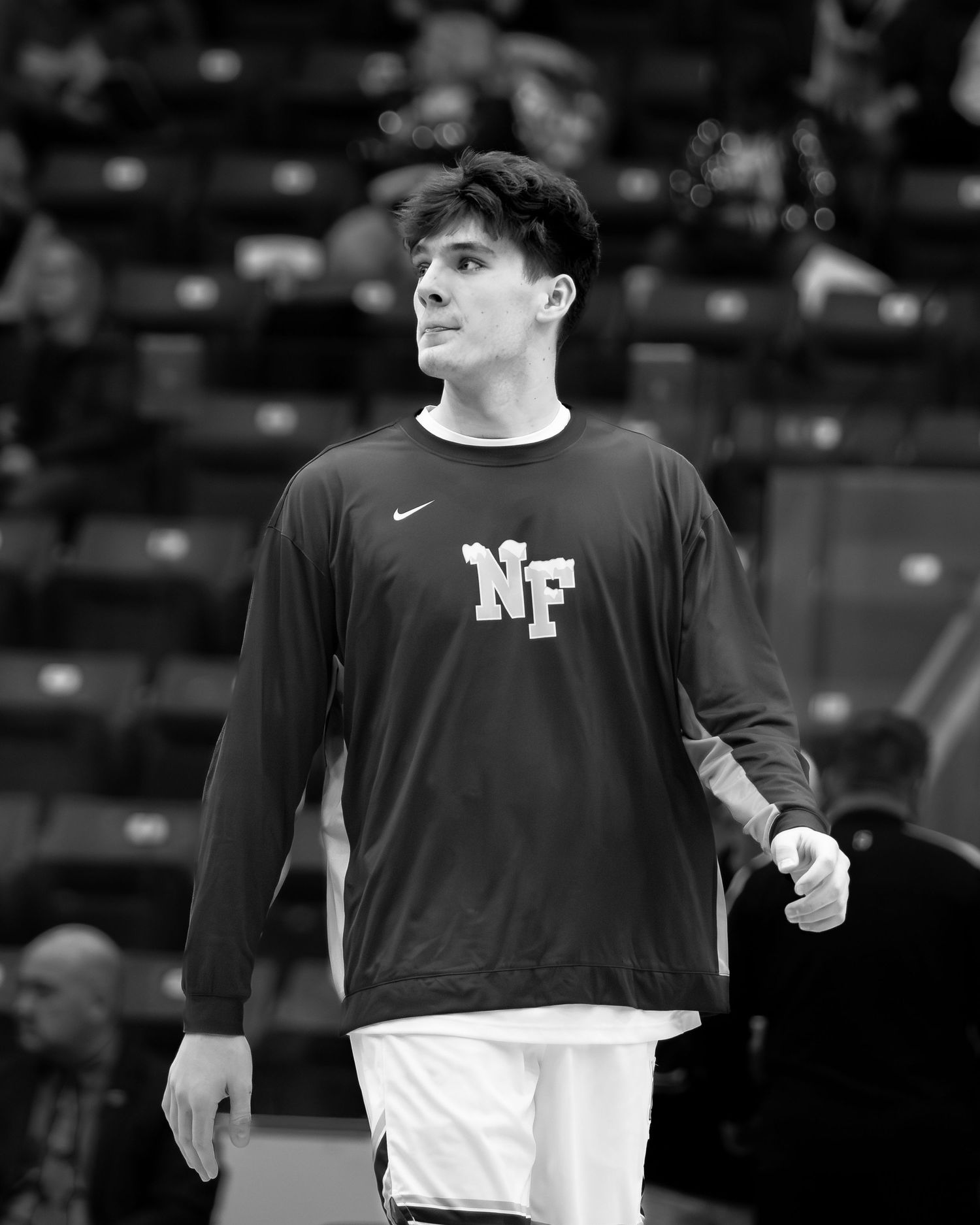 Black and white photo of a tall male basketball player wearing an NF Nike jersey.